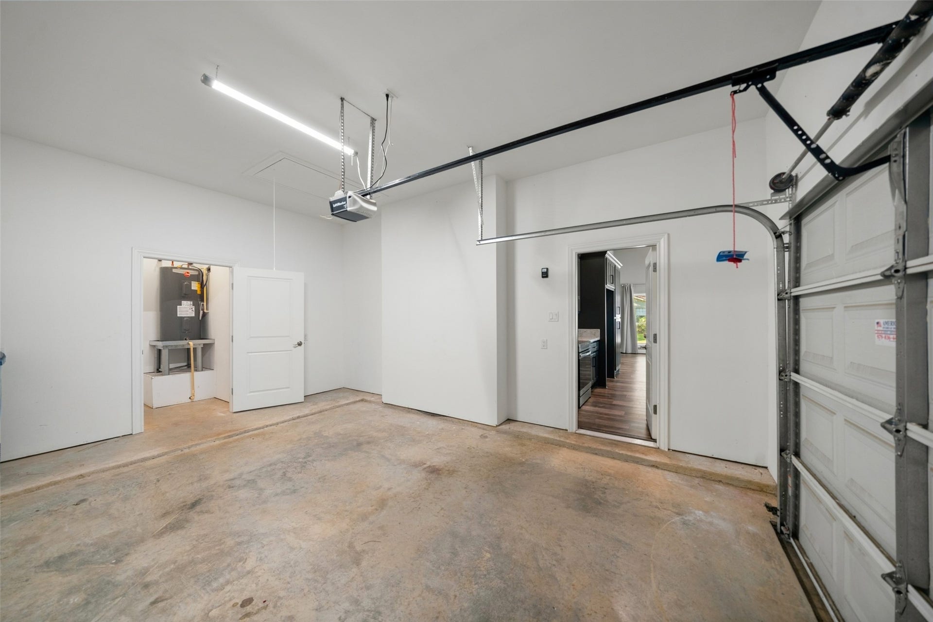 1125 Galveston Street, Hempstead, TX 77445 Garage featuring a concrete floor, overhead door with opener, and a water heater.