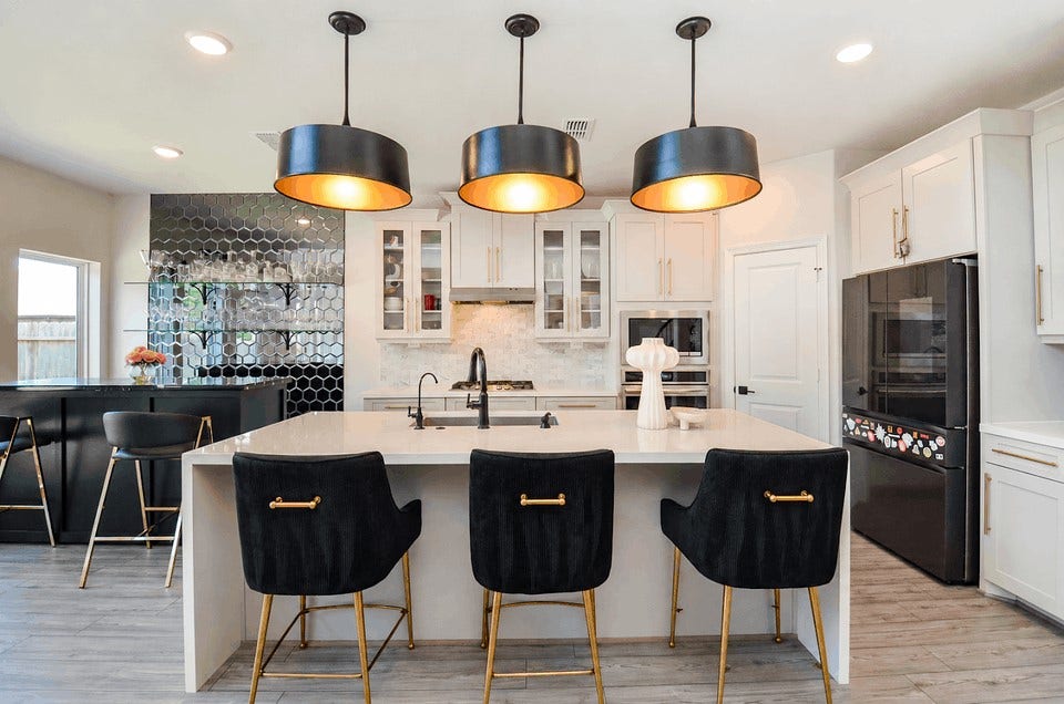 30706 Hawthorn Glen Court, Fulshear, TX 77441 Elegant kitchen with a spacious island, stylish black pendant lights, and luxurious bar seating. Features modern appliances, a sleek black hexagonal tile backsplash, and a convenient built-in bar area.