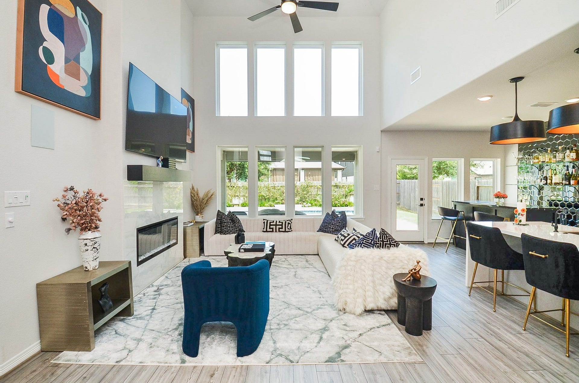 30706 Hawthorn Glen Court, Fulshear, TX 77441 Stunning open-concept living area with soaring ceilings, abundant natural light, and a sleek modern design. The space features a cozy fireplace, elegant furnishings, and a stylish bar area perfect for entertaining.