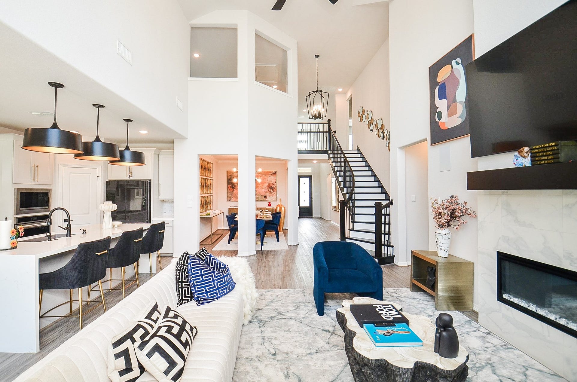 30706 Hawthorn Glen Court, Fulshear, TX 77441 Stunning open-concept living space featuring soaring ceilings, a modern kitchen with chic pendant lighting, and a cozy fireplace. The elegant staircase leads to a second level, while the dining area is perfect for entertaining.