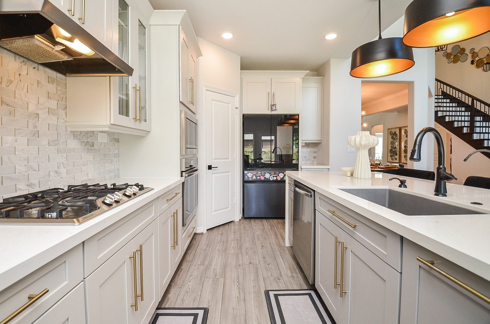 30706 Hawthorn Glen Court, Fulshear, TX 77441 Sleek modern kitchen featuring elegant cabinetry, a spacious island with a sink, stylish pendant lighting, and a high-end stovetop, all accentuated by a chic tile backsplash.