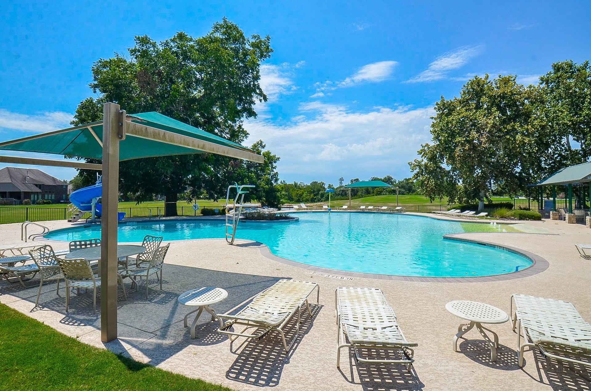 30706 Hawthorn Glen Court, Fulshear, TX 77441 Experience relaxation at this inviting outdoor pool, complete with shaded seating, lush greenery, and a fun water slide.