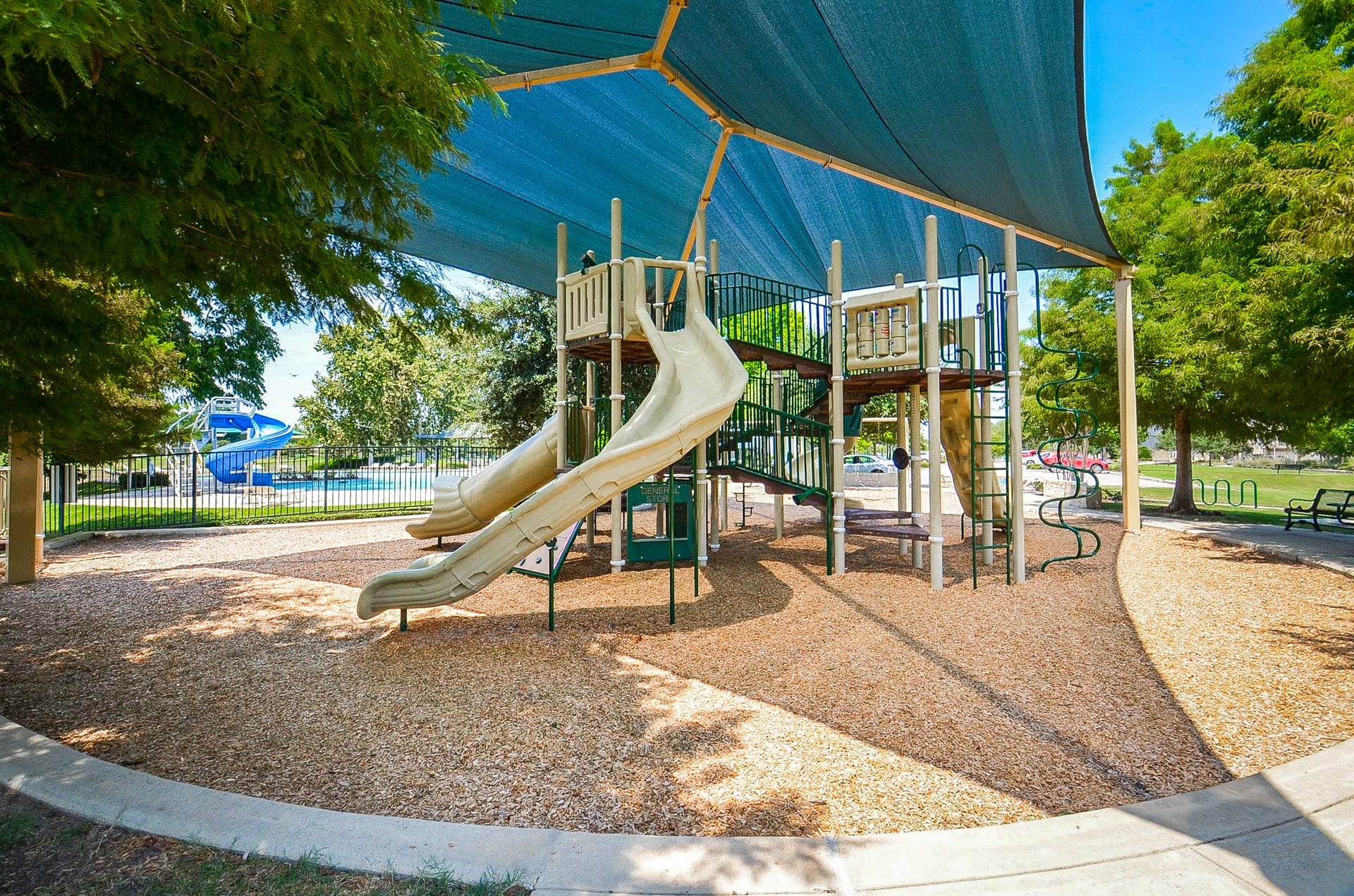 30706 Hawthorn Glen Court, Fulshear, TX 77441 A well-shaded playground with slides and climbing structures, perfect for family fun, nestled in a beautifully landscaped park setting.