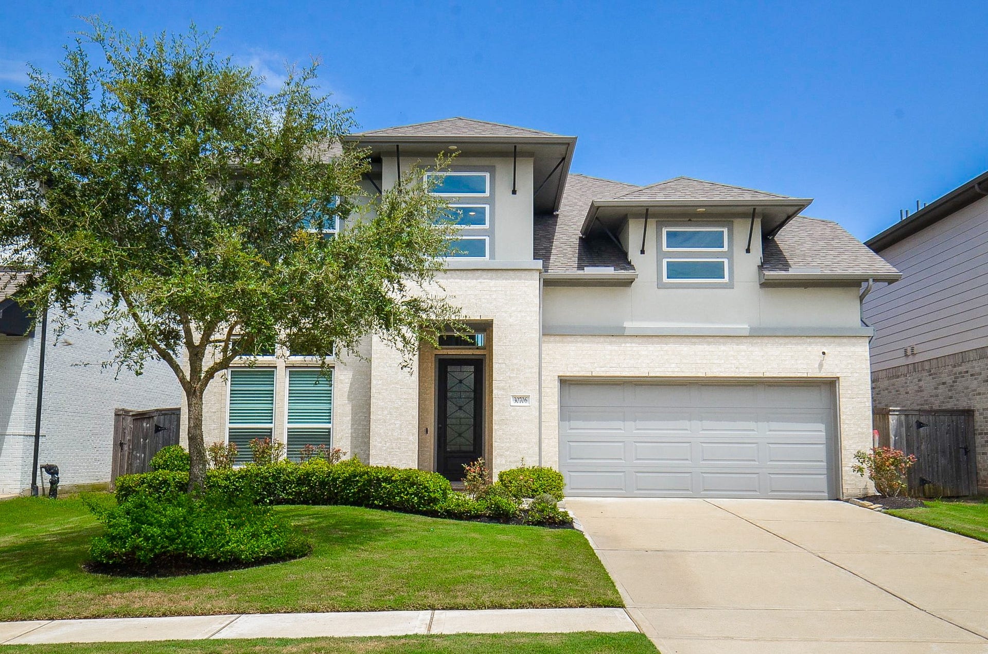 30706 Hawthorn Glen Court, Fulshear, TX 77441 Modern two-story home with a sleek facade, featuring a spacious two-car garage and well-maintained landscaping.