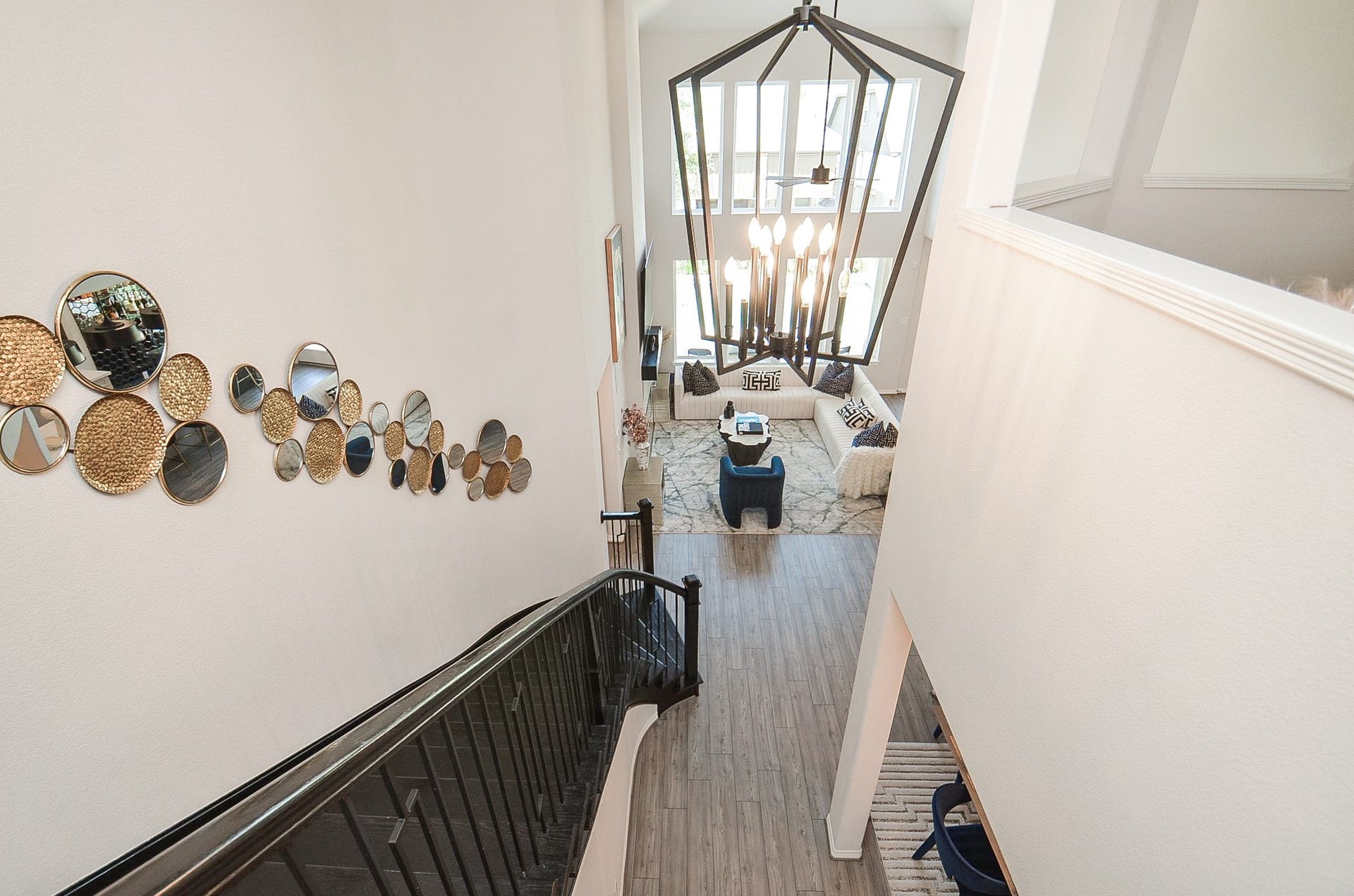30706 Hawthorn Glen Court, Fulshear, TX 77441 Elegant two-story foyer with a striking modern chandelier, artistic wall accents, and a view of the spacious, sunlit living area below.
