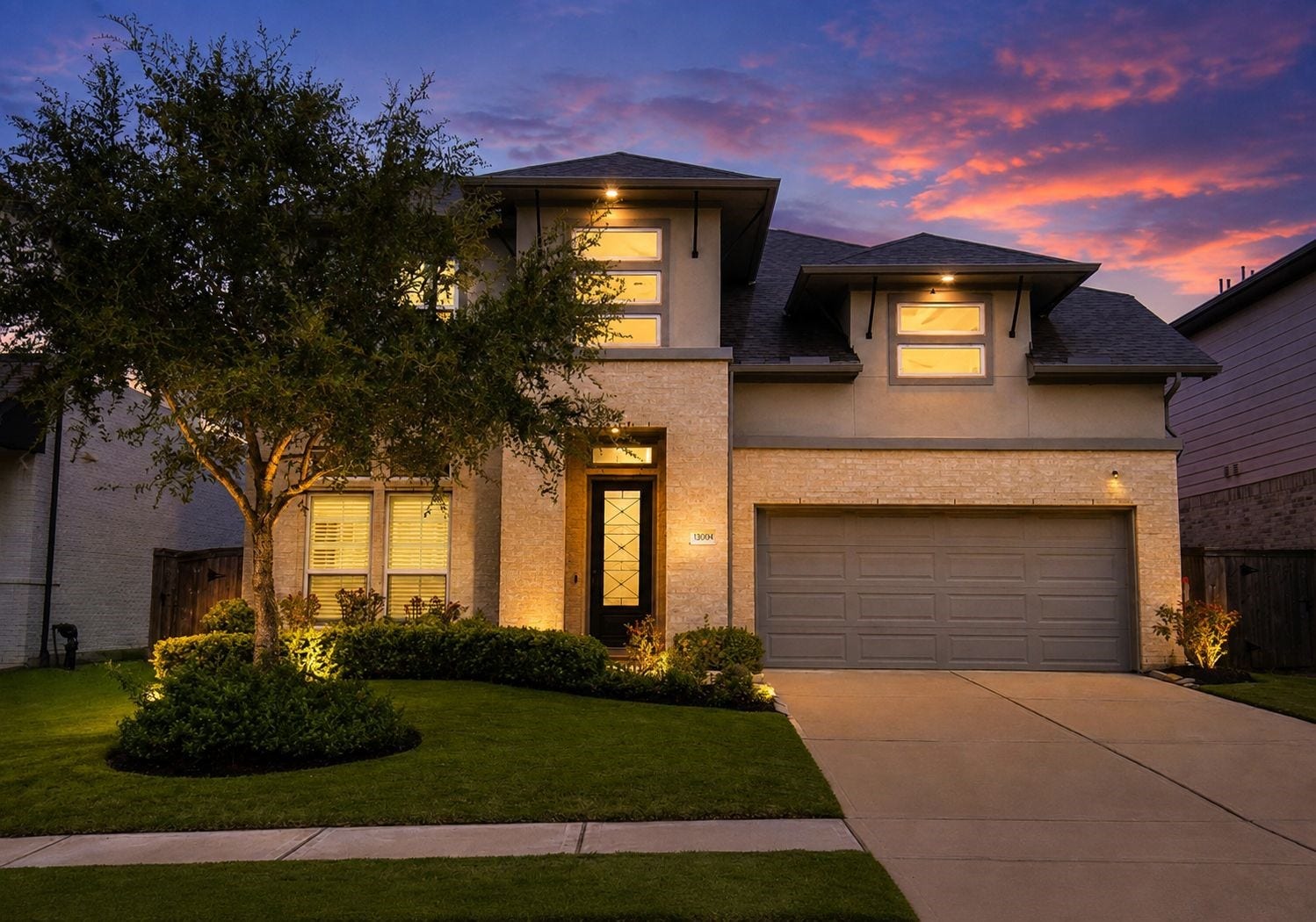 30706 Hawthorn Glen Court, Fulshear, TX 77441 Stunning two-story home with modern architecture, beautifully lit against a vibrant sunset. Features a spacious two-car garage, manicured lawn, and inviting entryway.
