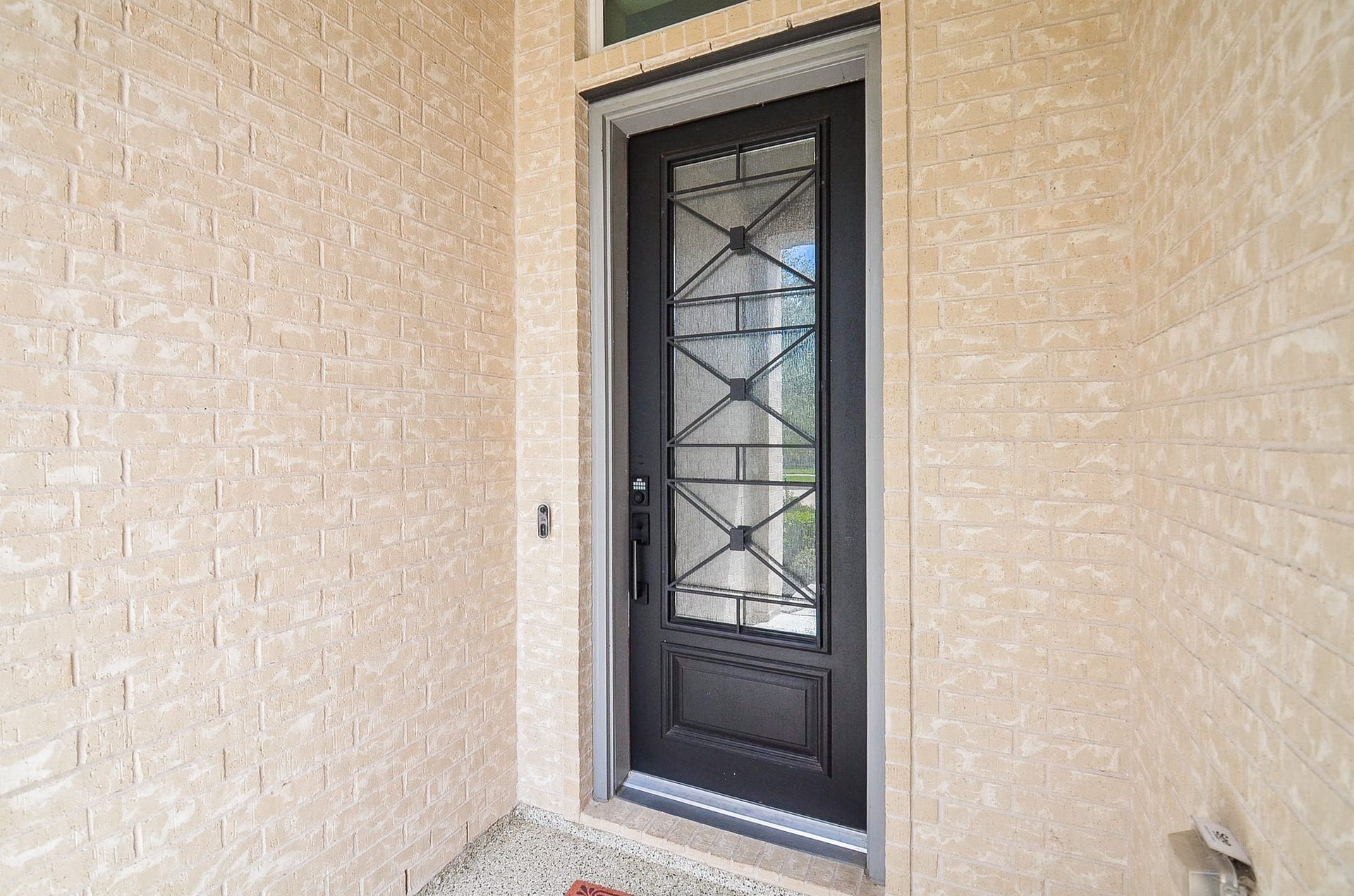 30706 Hawthorn Glen Court, Fulshear, TX 77441 Elegant brick entryway featuring a striking black door with decorative glass, offering a welcoming and secure entrance.