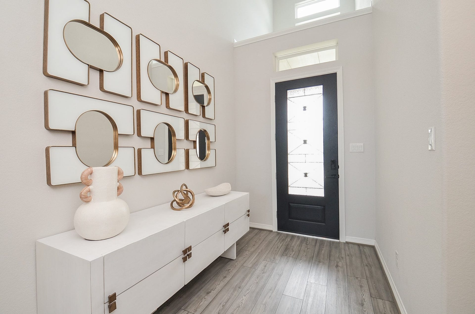 30706 Hawthorn Glen Court, Fulshear, TX 77441 Elegant two-story foyer with a striking modern chandelier, artistic wall accents, and a view of the spacious, sunlit living area below.