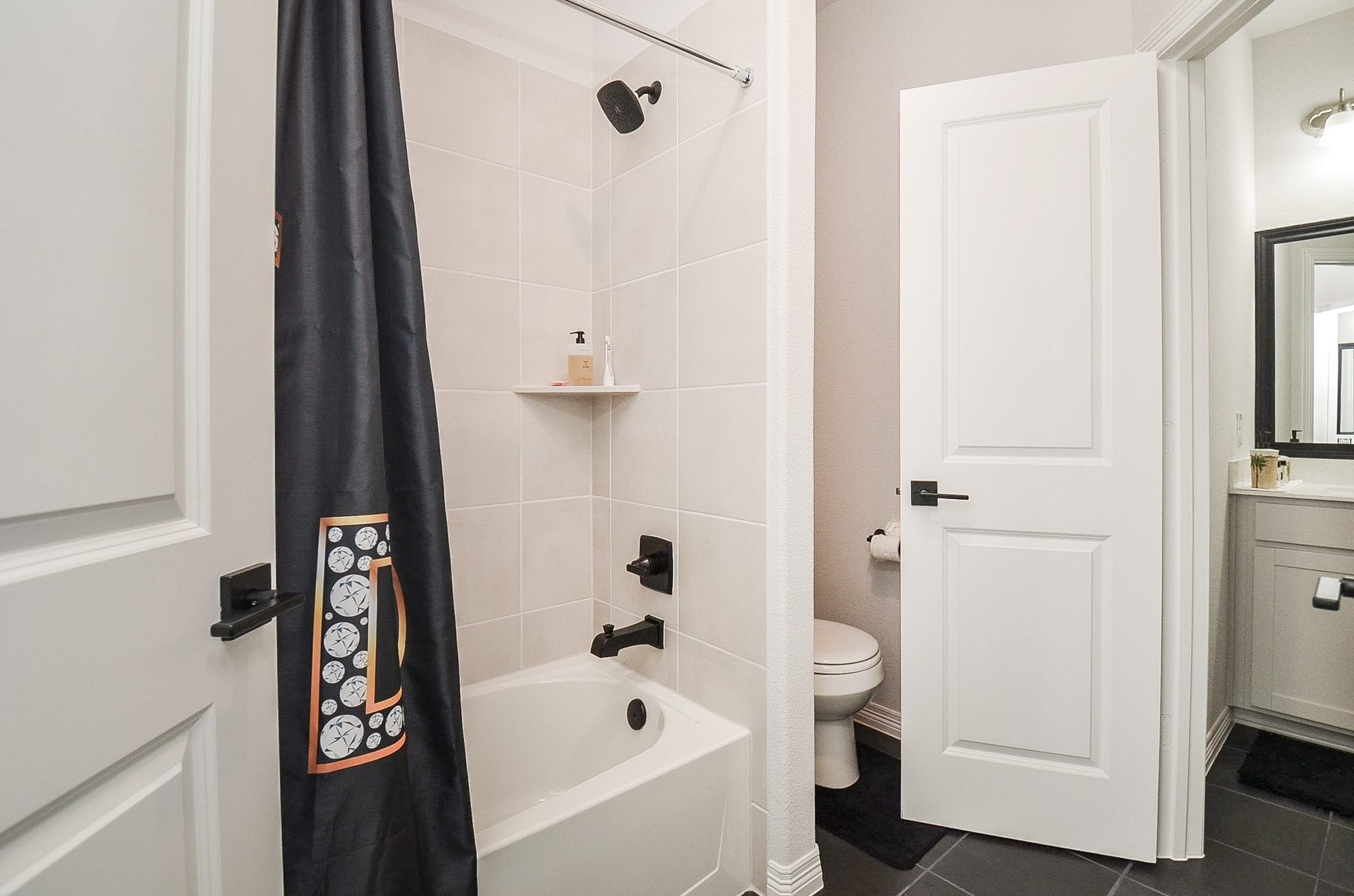 30706 Hawthorn Glen Court, Fulshear, TX 77441 Chic bathroom featuring a modern tub and shower combo with sleek black fixtures, complemented by a stylish vanity area with ample lighting.