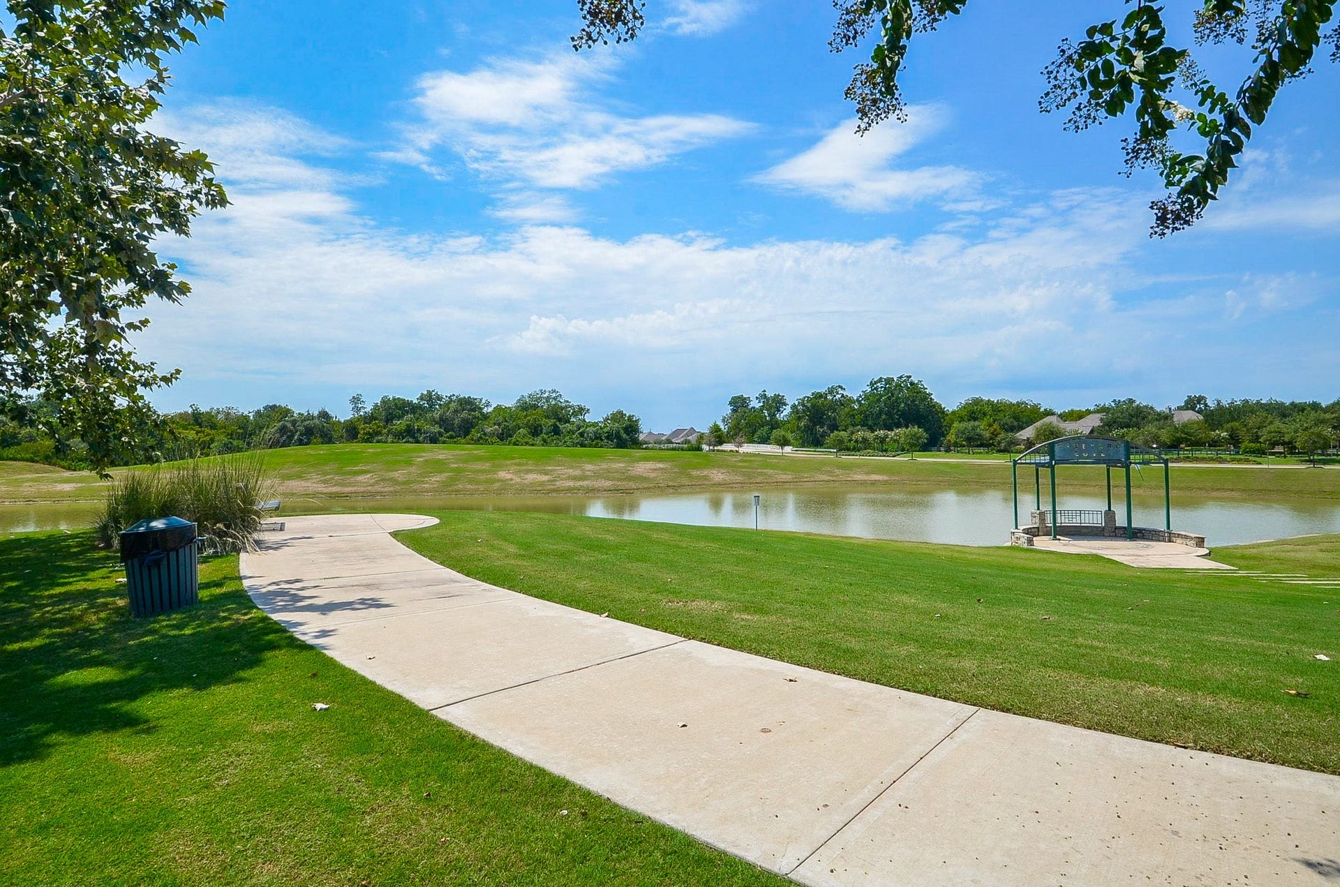 30706 Hawthorn Glen Court, Fulshear, TX 77441 Scenic pathway alongside a tranquil pond, perfect for leisurely walks and enjoying nature.