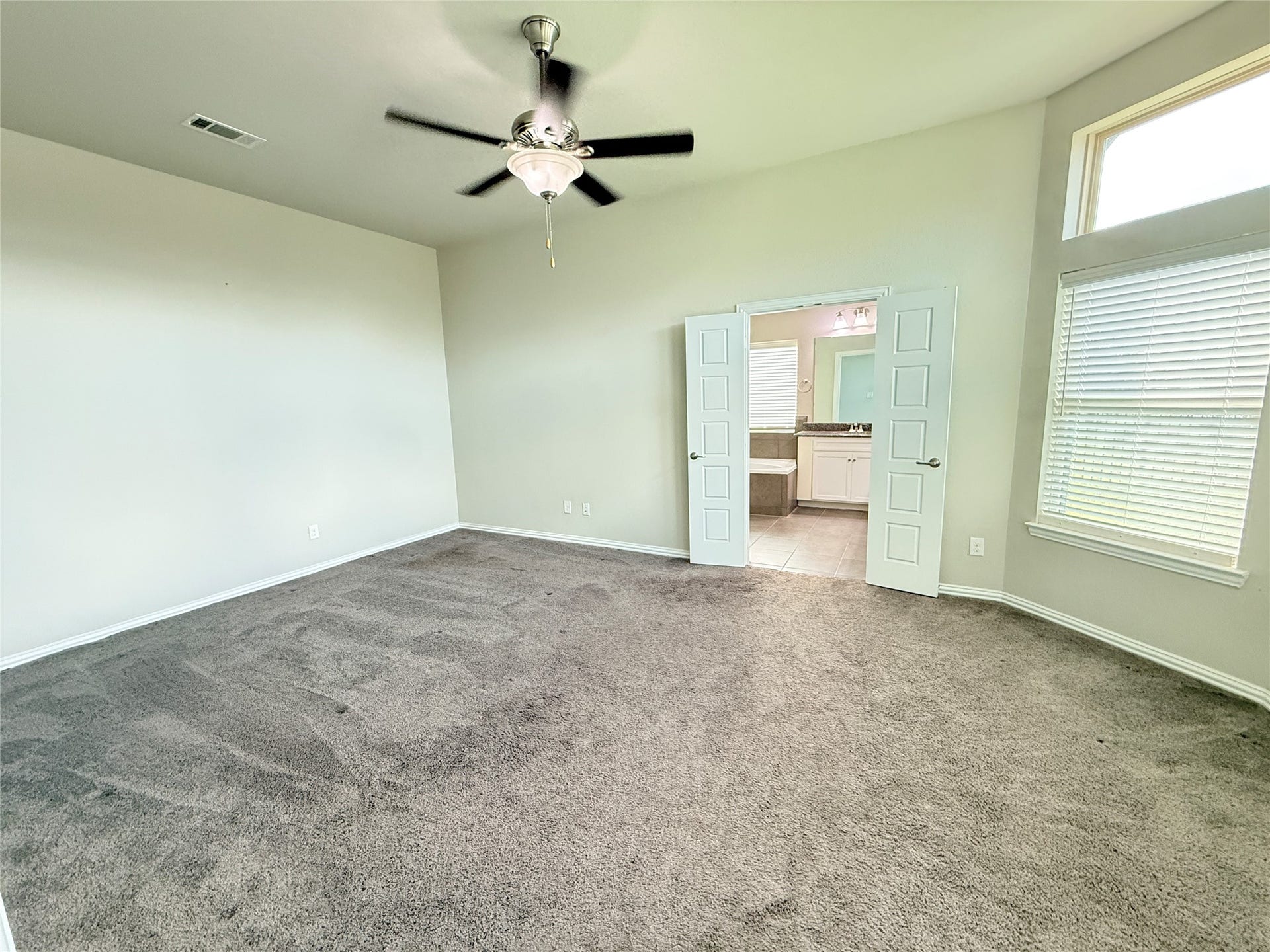 20635 Riley Copper Drive, Cypress, TX 77433 Supersized primary bedroom with high ceilings, a ceiling fan and a bright bay window looking out onto the lake.