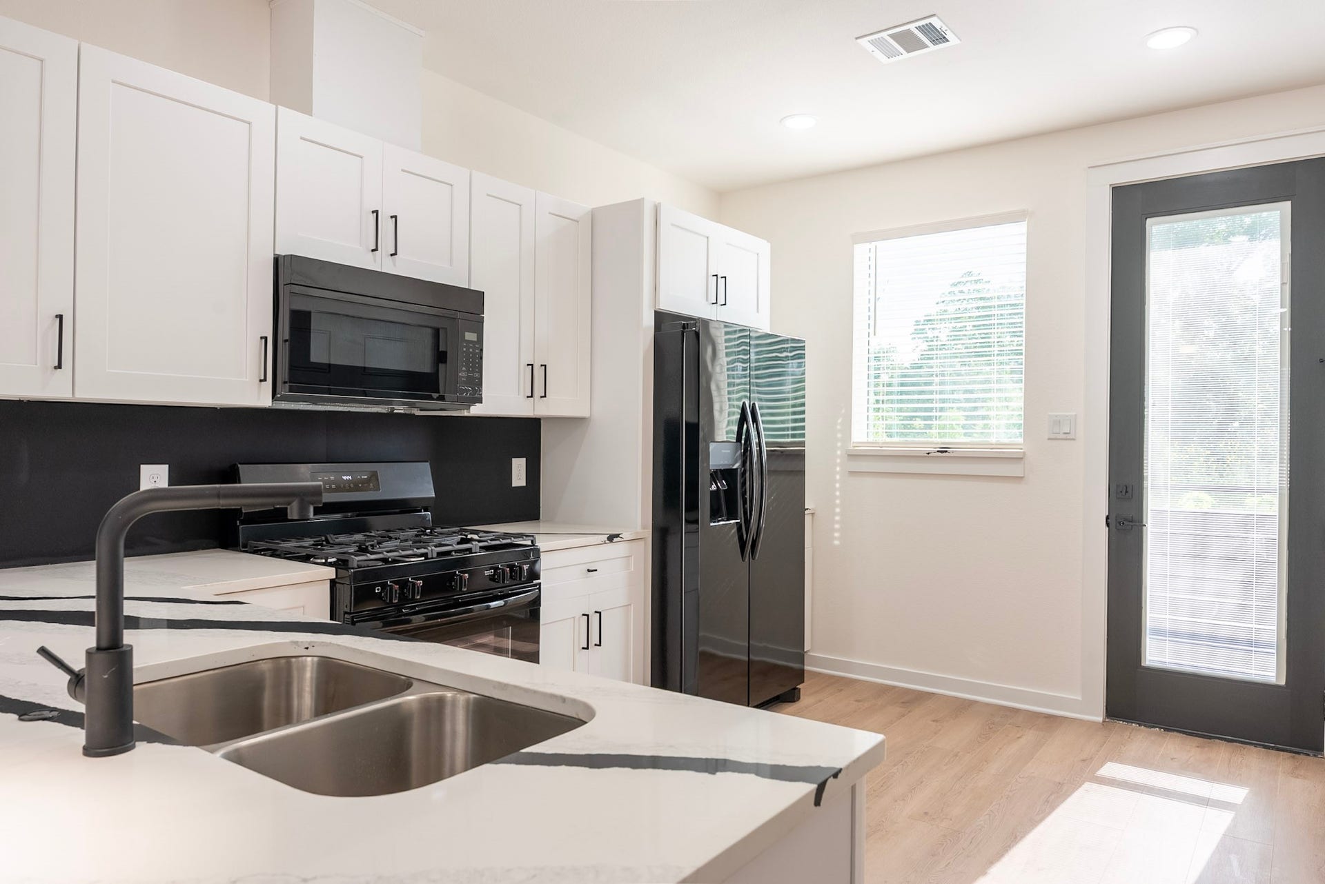 3522 Mansfield Building H Street, #C, Houston, TX 77091 Modern kitchen featuring sleek black appliances, elegant white cabinetry, and a stylish quartz countertop with a dual sink.