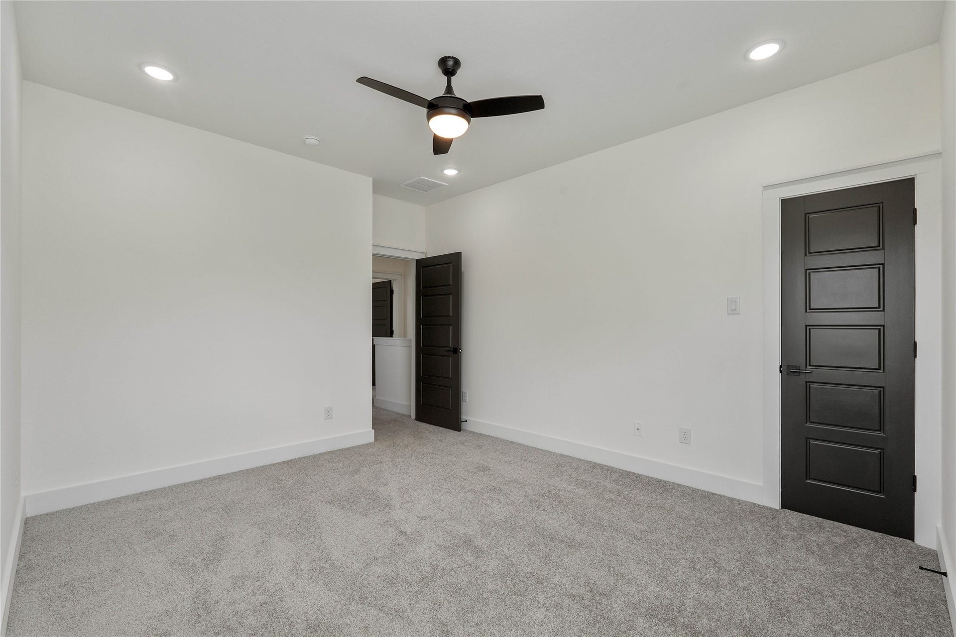 3522 Mansfield Building H Street, #C, Houston, TX 77091 Spacious, light filled room with plush carpeting, modern ceiling fan, and sleek black doors creating a sophisticated contrast.
