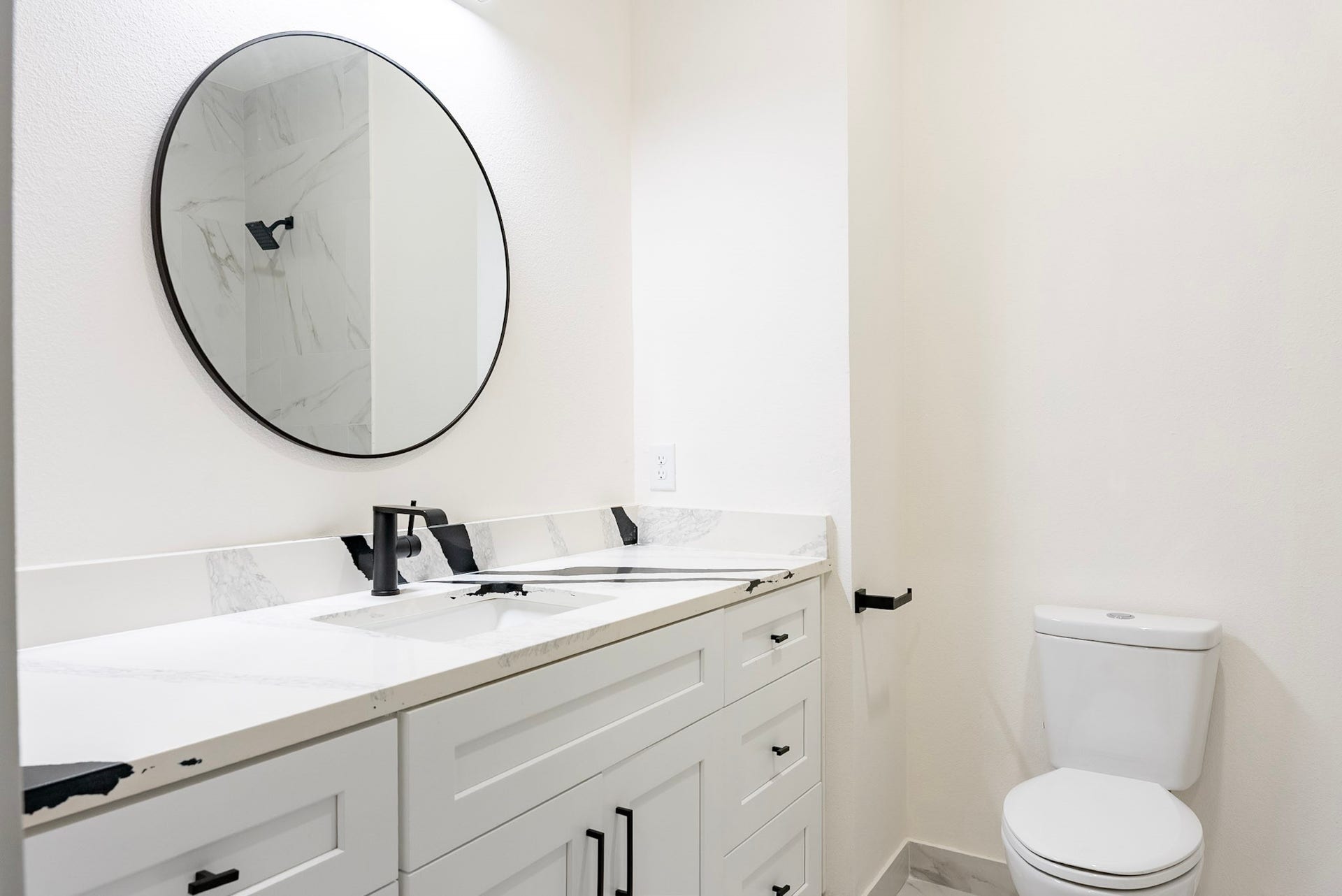 3522 Mansfield Building H Street, #C, Houston, TX 77091 Modern bathroom featuring a sleek vanity with quartz countertop, stylish black fixtures, and a large round mirror for an elegant touch.
