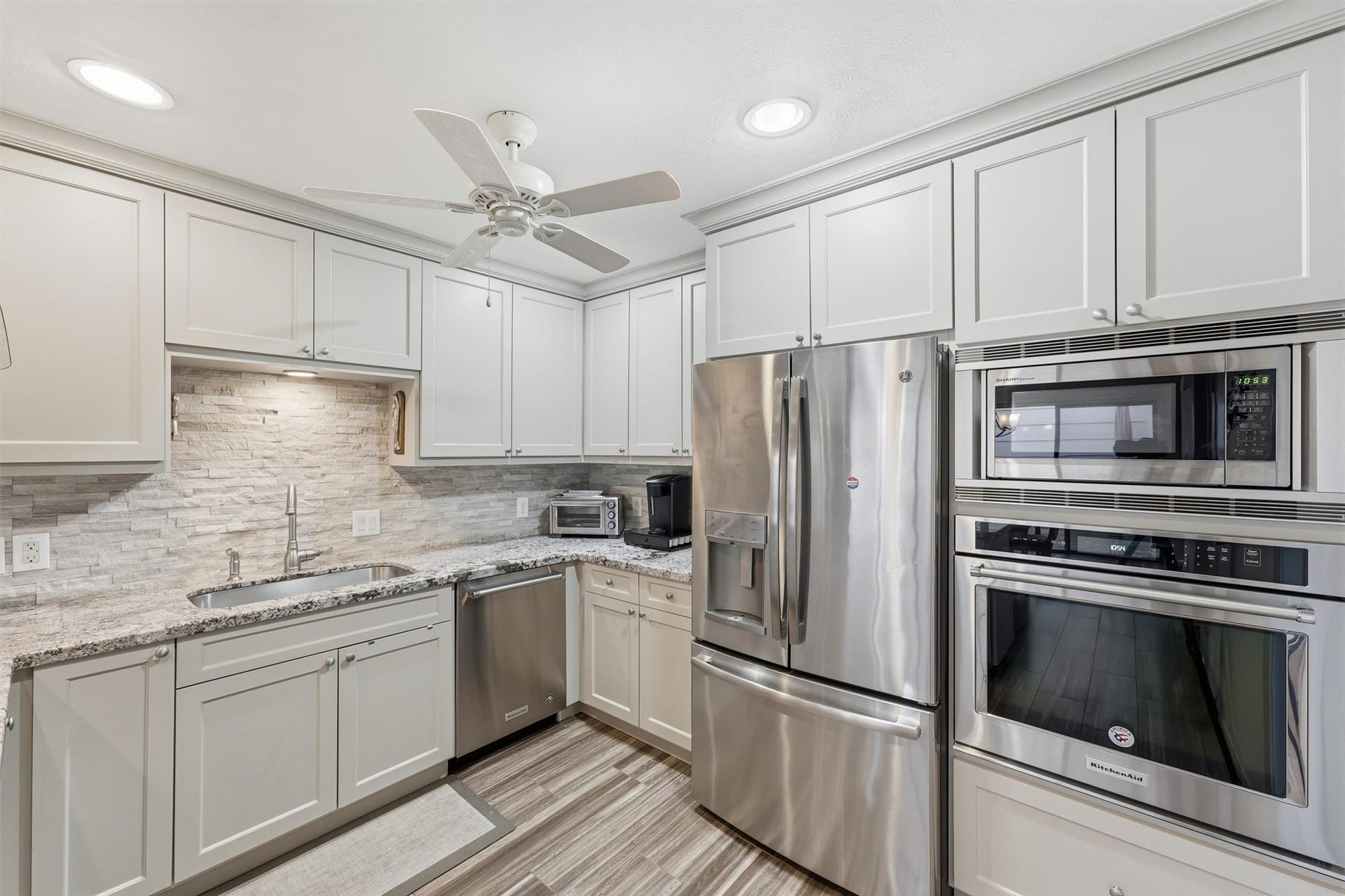 Kitchen is a dream with plenty of counter & cabinet space, KitchenAid oven & dishwasher, large undermount sink, neutral tile backsplash & more!