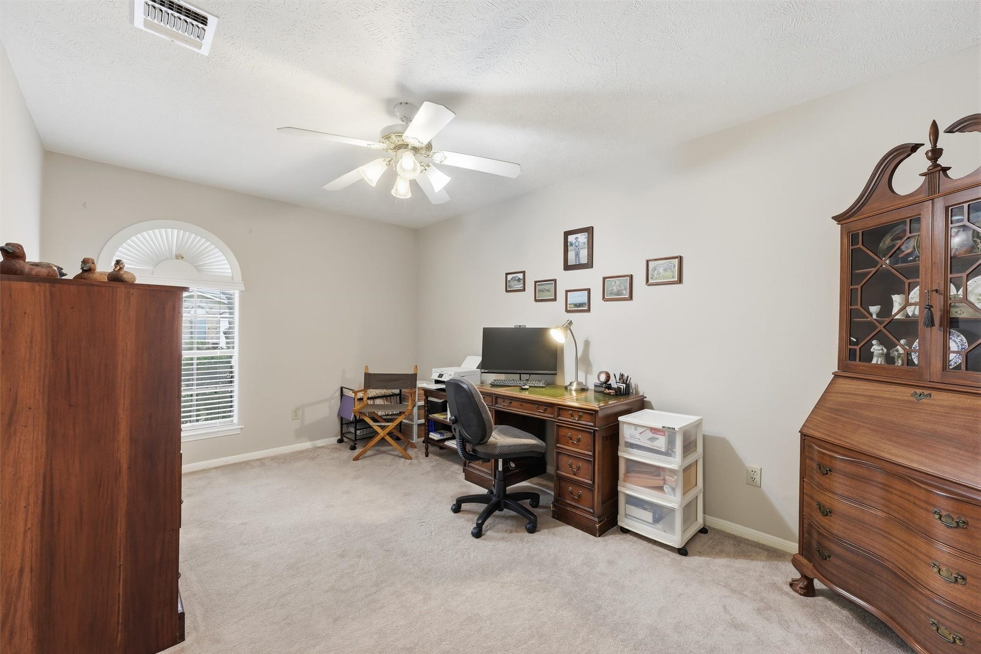 The split floor plan offers two flexible secondary bedrooms at the front of the home.  This one is currently used as an office space & features a ceiling fan & walk-in closet with shelving.