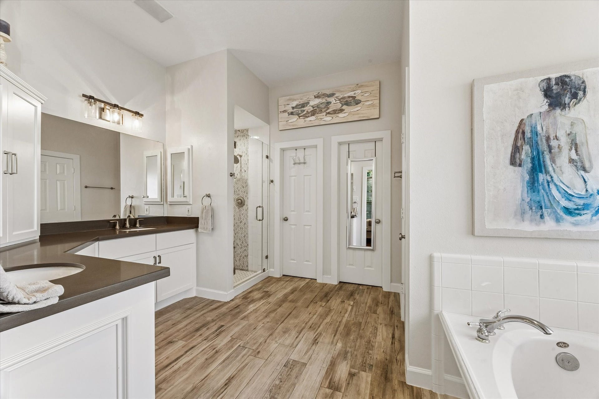 3615 Garrettsville Drive, Pearland, TX 77584 Primary bathroom featuring double vanities, jetted tub, and a separate glass-enclosed shower, all complemented by modern fixtures. There are two separate walk in closets at the end of the bathroom.