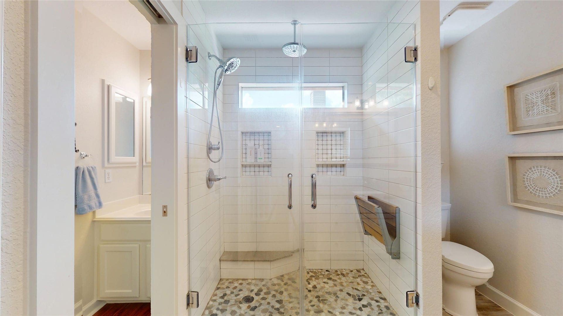 3615 Garrettsville Drive, Pearland, TX 77584 Renovated bathroom featuring a spacious glass-enclosed shower with sleek fixtures and a pebble stone floor, complemented by a modern vanity and soothing neutral tones.