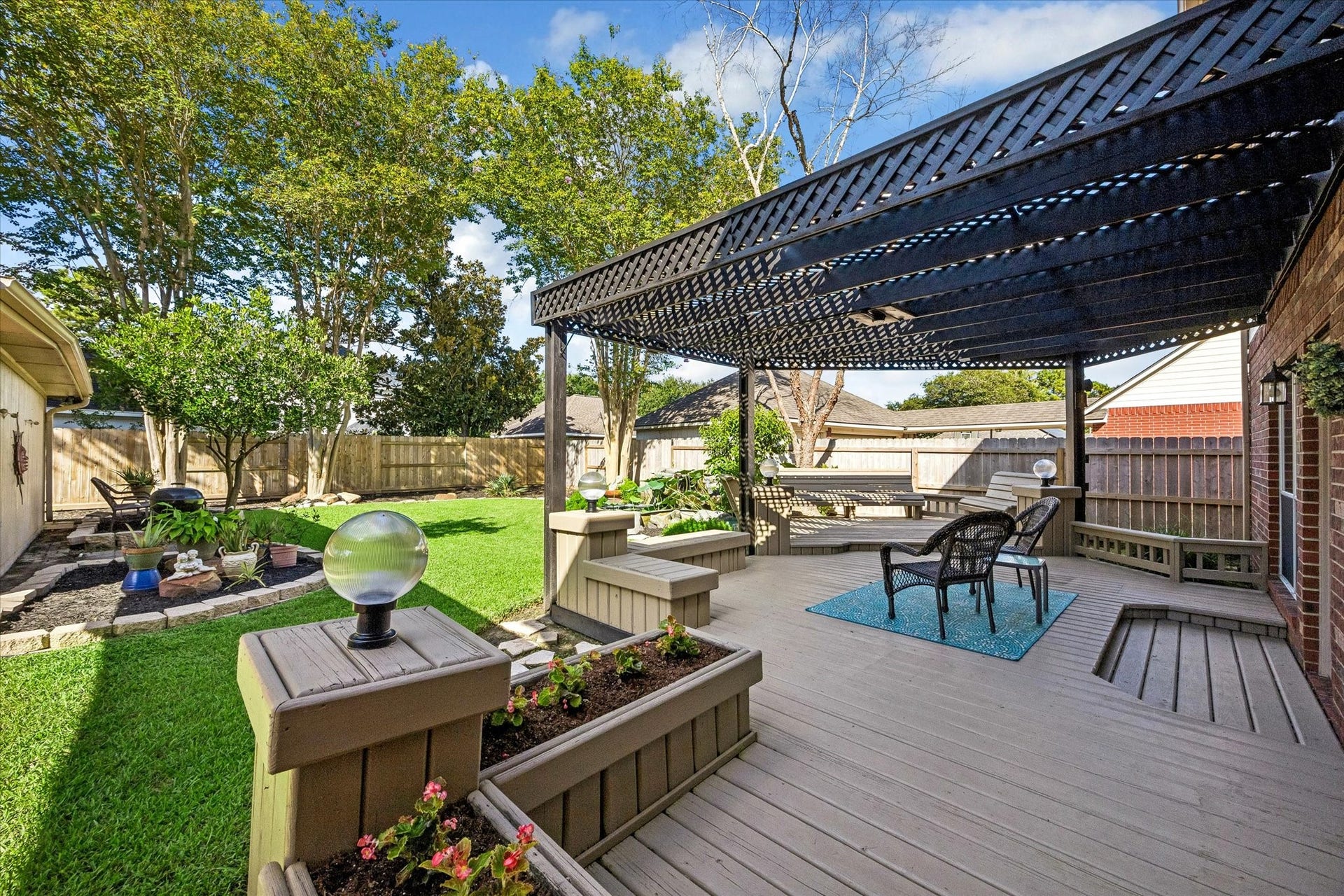 3615 Garrettsville Drive, Pearland, TX 77584 Spacious backyard oasis featuring a stylish pergola-covered deck with built-in benches, koi fish pond, lush green lawn, and charming garden beds, perfect for outdoor relaxation and entertaining.