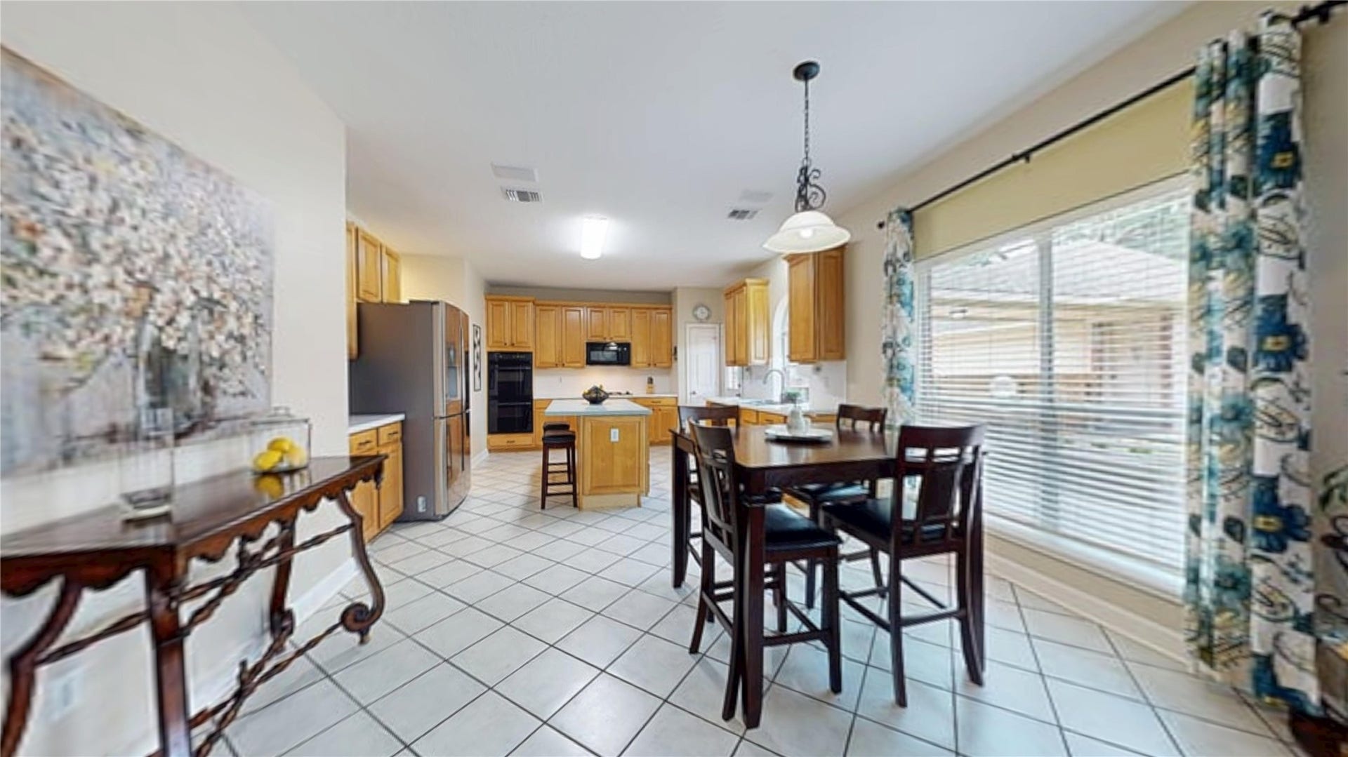 3615 Garrettsville Drive, Pearland, TX 77584 Bright kitchen and dining area featuring tiled floors, wooden cabinetry, and a spacious island, with large windows offering abundant natural light.