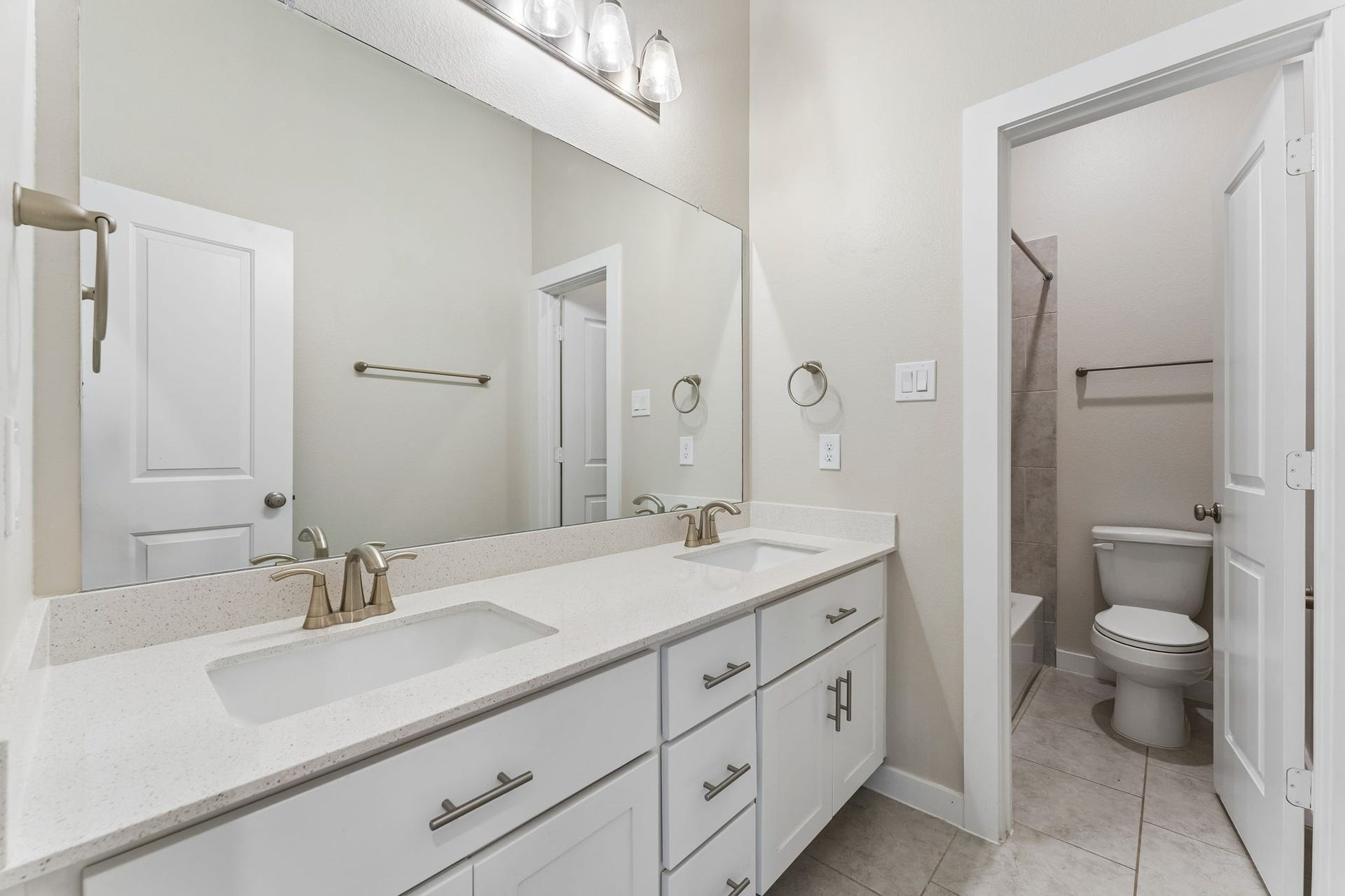 30410 Myrtle Oak Drive, Fulshear, TX 77423 The secondary bathroom is thoughtfully designed for modern living, featuring dual vanity sinks that provide ample space for multiple users, alongside a private, separate water closet that ensures maximum privacy and convenience for the entire family during busy morning routines.