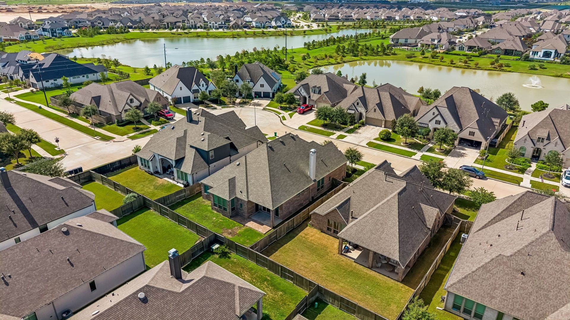 30410 Myrtle Oak Drive, Fulshear, TX 77423 Stunning view from the rear of the home, showcasing the serene community lakes and the beautiful, lush surroundings of the Jordan Ranch neighborhood.