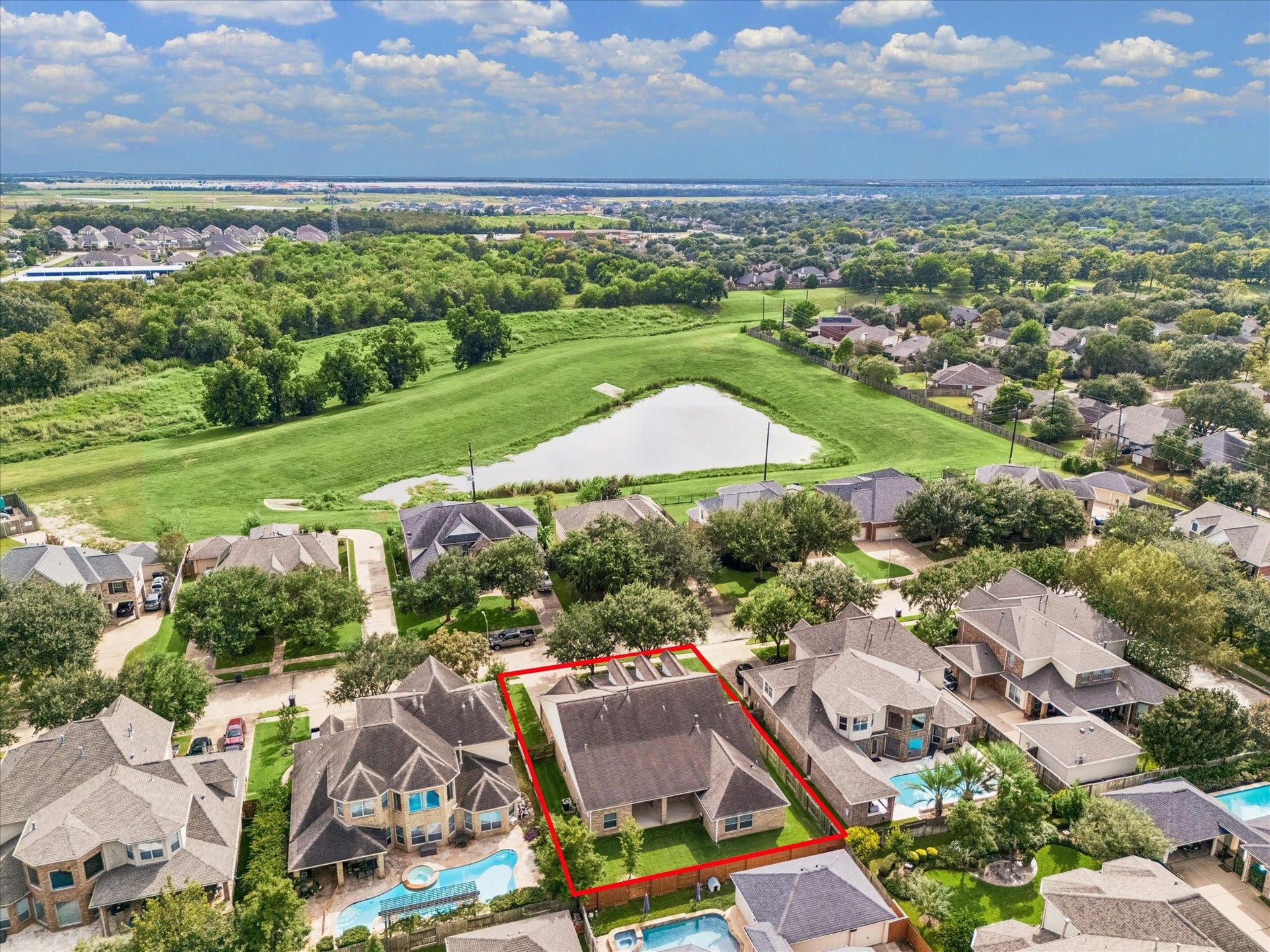 7715 BAYOU GREEN LANE, Sugar Land, TX 77479 AERIAL VIEW HIGHLIGHTS THE HOMES PRIME NEIGHBORHOOD SETTING, WITH EXPANSIVE GREEN SPACE AND A SCENIC POND NEARBY.