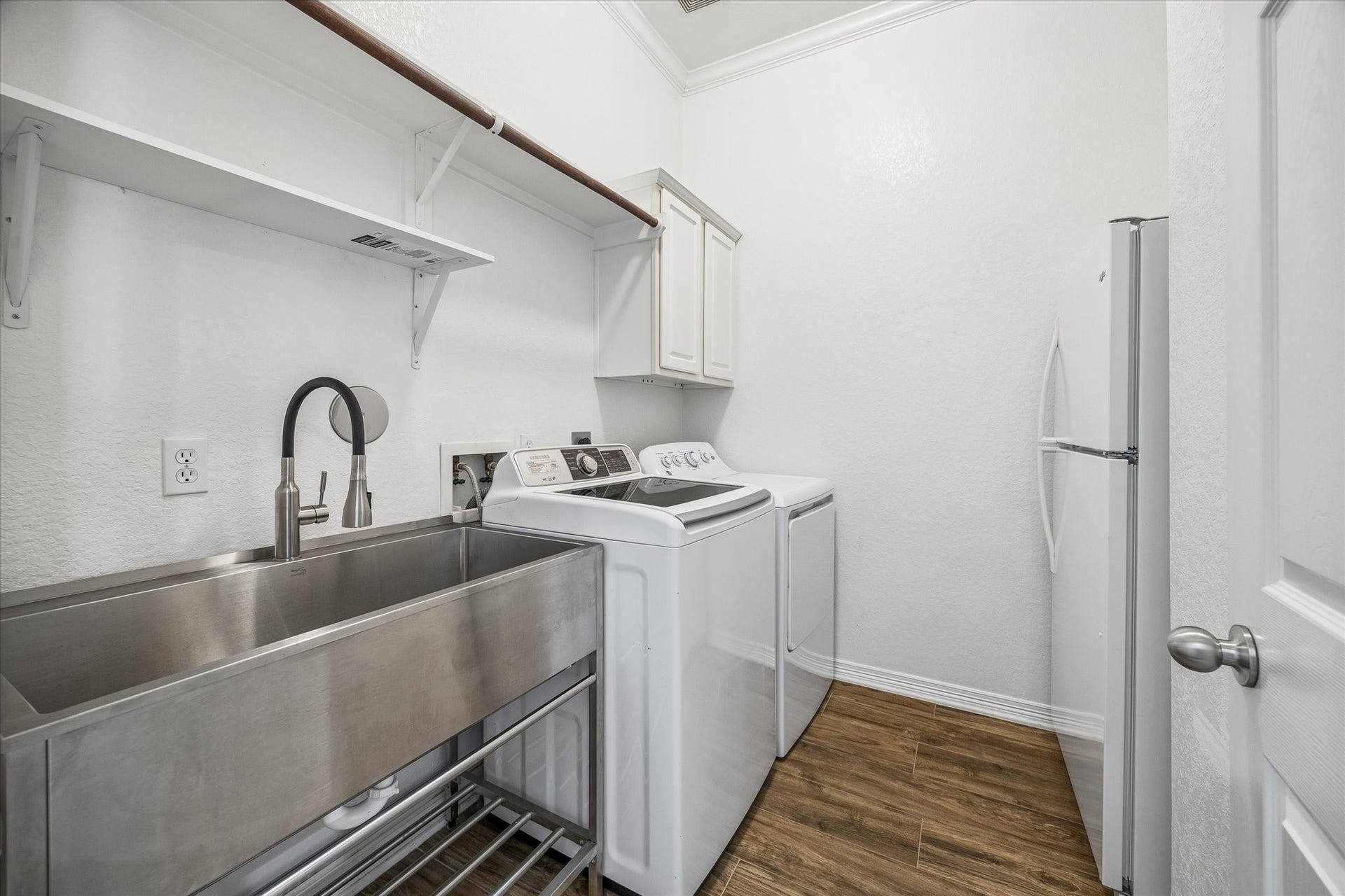 7715 BAYOU GREEN LANE, Sugar Land, TX 77479 FUNCTIONAL LAUNDRY ROOM WITH FULL-SIZE WASHER/DRYER SPACE, DEEP UTILITY SINK, BUILT-IN STORAGE, AND ROOM FOR AN EXTRA REFRIGERATOR.