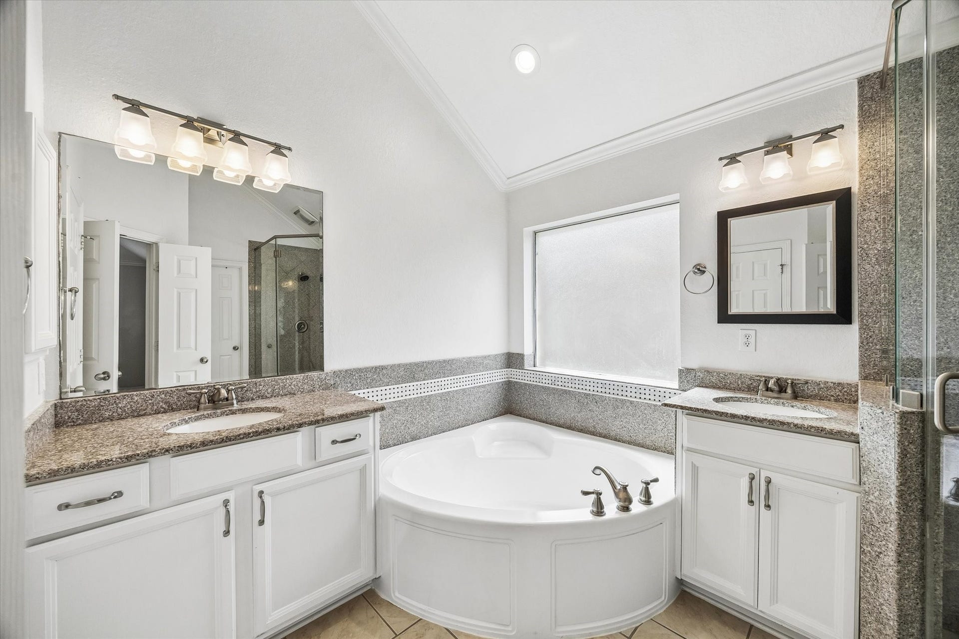 7715 BAYOU GREEN LANE, Sugar Land, TX 77479 PRIMARY BATH WITH DUAL VANITIES, GRANITE COUNTERS, A CORNER SOAKING TUB, AND SEPARATE GLASS-ENCLOSED SHOWER.