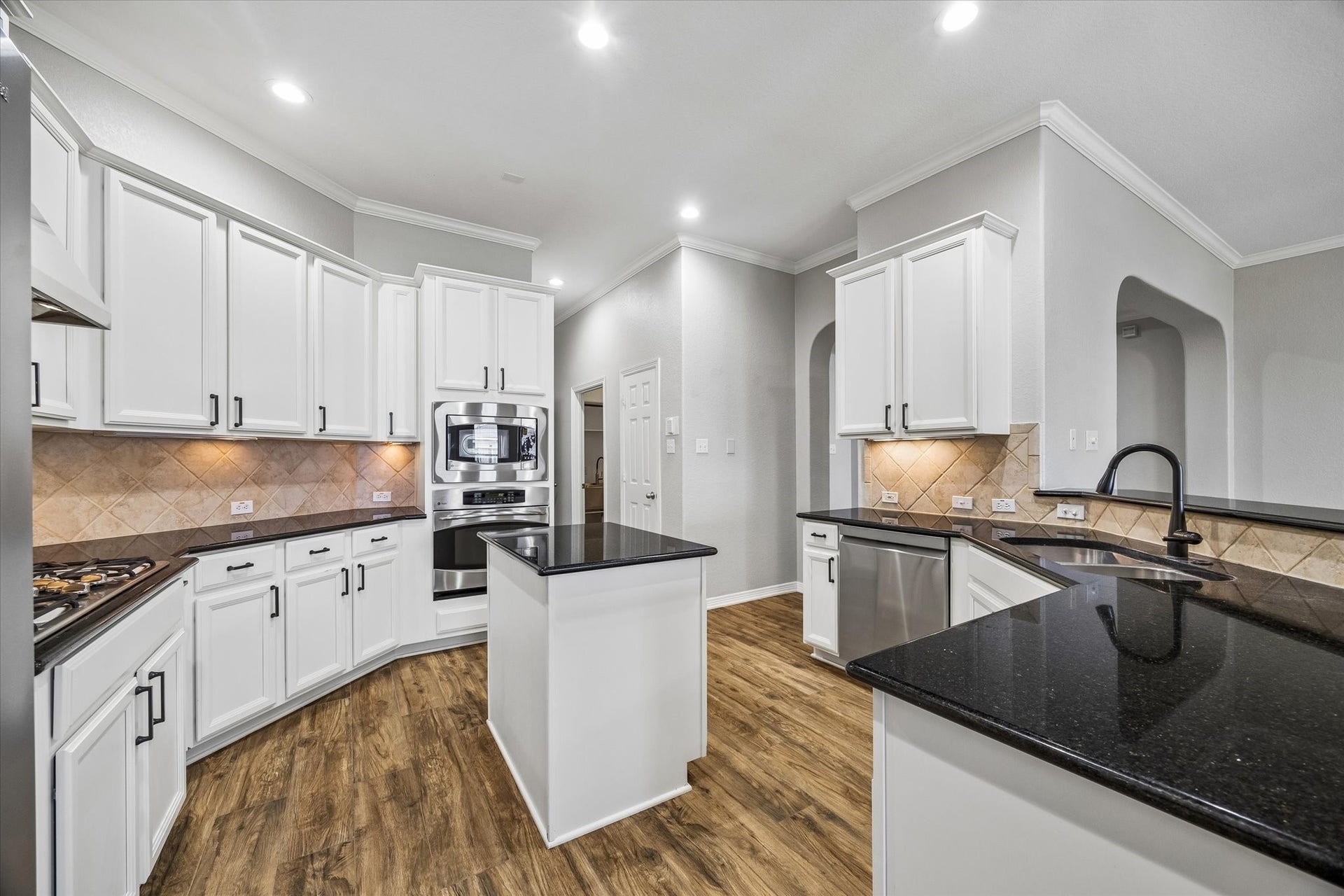 7715 BAYOU GREEN LANE, Sugar Land, TX 77479 BRIGHT KITCHEN WITH CRISP WHITE CABINETRY, GRANITE COUNTERTOPS, STAINLESS STEEL APPLIANCES, GAS COOKTOP, AND GENEROUS PREP SPACE.