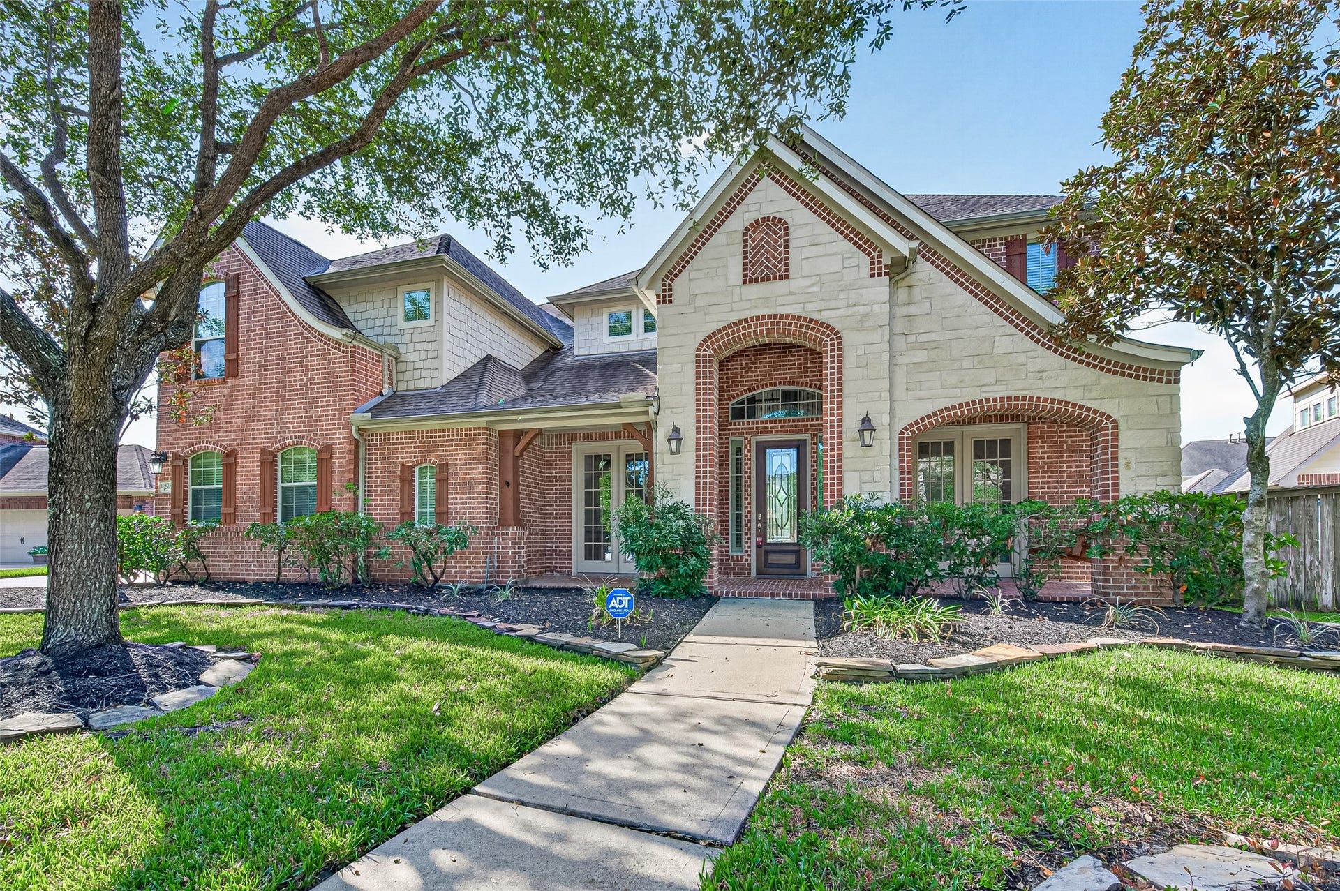 11803 Silverwood Bend Lane, Cypress, TX 77433 Charming two-story home with a blend of brick and stone exterior, featuring a welcoming arched entryway and lush landscaping.