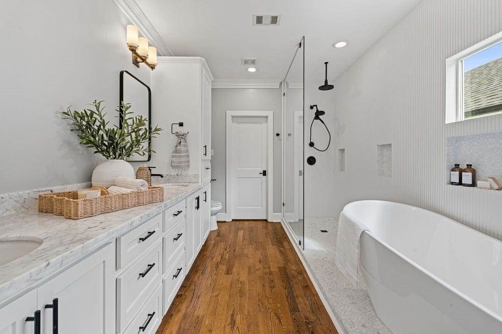 Spa-inspired primary bathroom with an expansive double vanity, freestanding soaking tub, and separate shower.