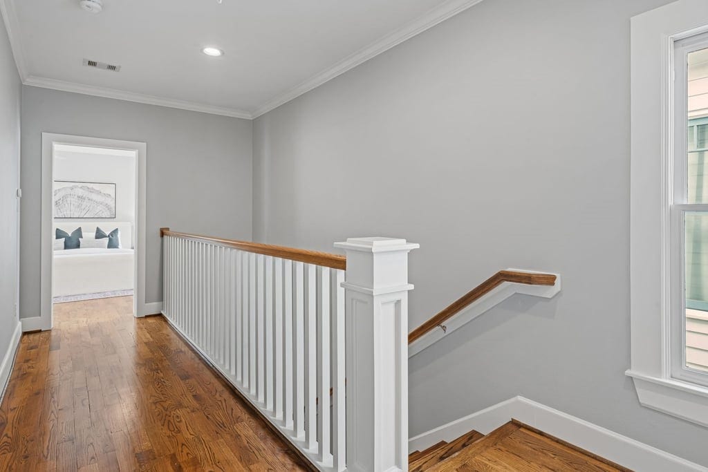 Sunlit upper landing with traditional staircase millwork and warm hardwood flooring.