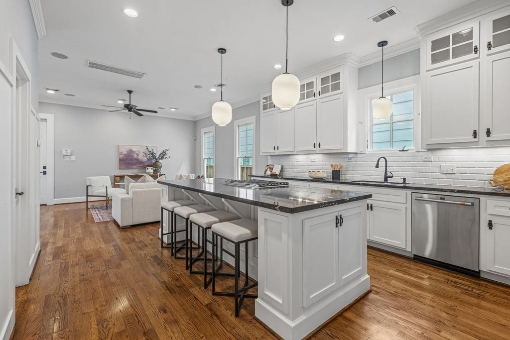 Beautifully appointed kitchen with white cabinetry, dark countertops, and a generous entertaining island.