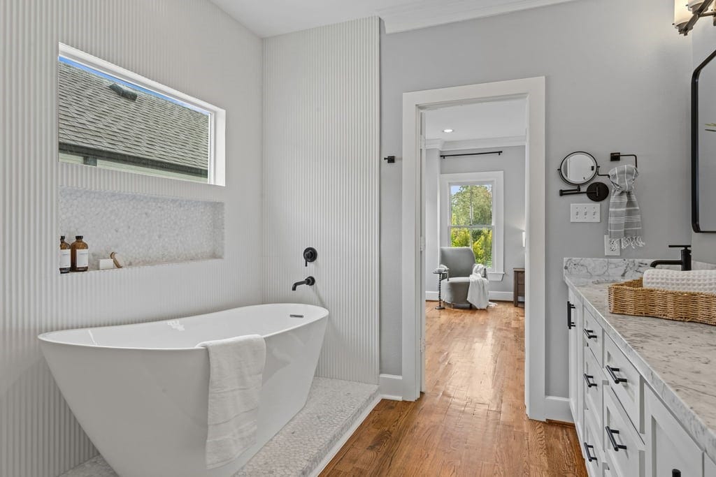 Freestanding soaking tub beneath a picture window creates a tranquil place to unwind.