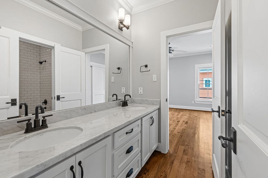 Secondary bathroom featuring a double-sink vanity, stone-look counters, and timeless finishes.