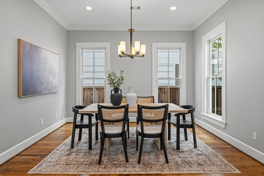 Sunlit formal dining room with an elegant chandelier and beautiful hardwood floors.