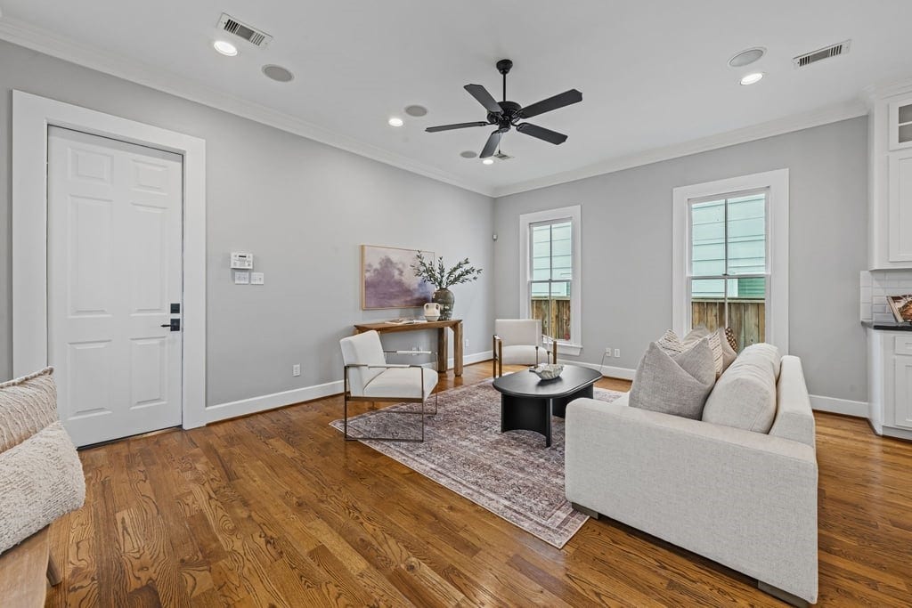 Light-filled living room with high ceilings, rich hardwood flooring, and an open, airy atmosphere.