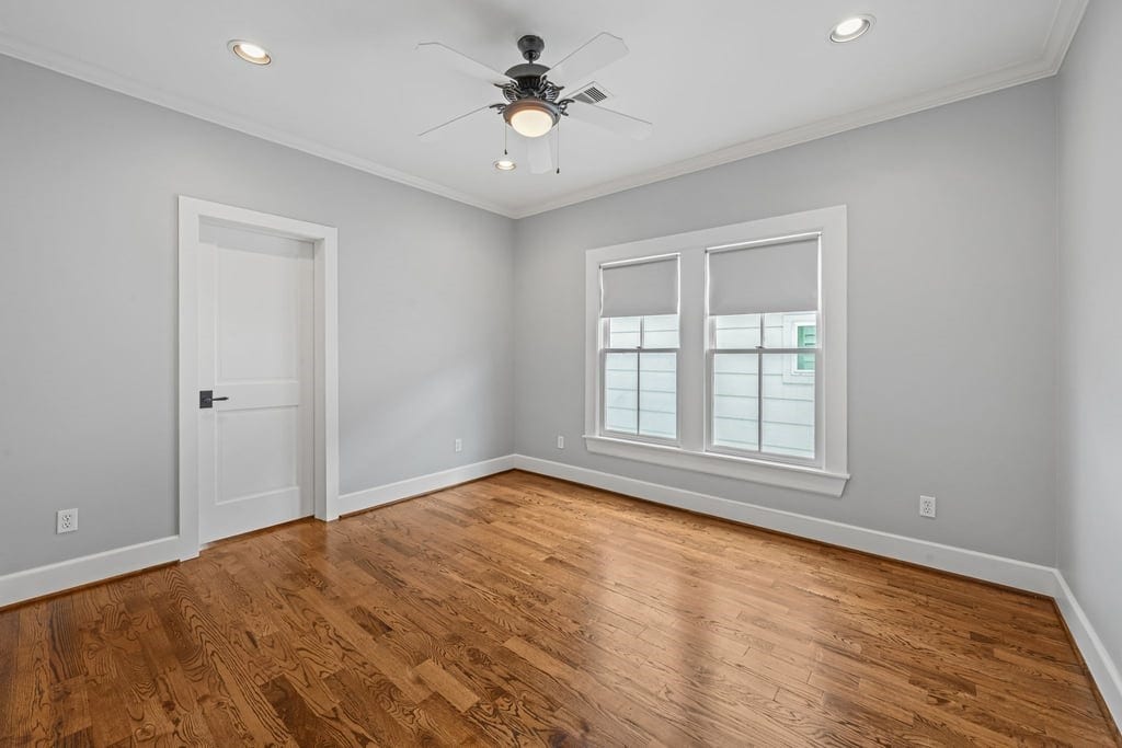 Spacious secondary bedroom with hardwood floors, ceiling fan, and ample natural light.