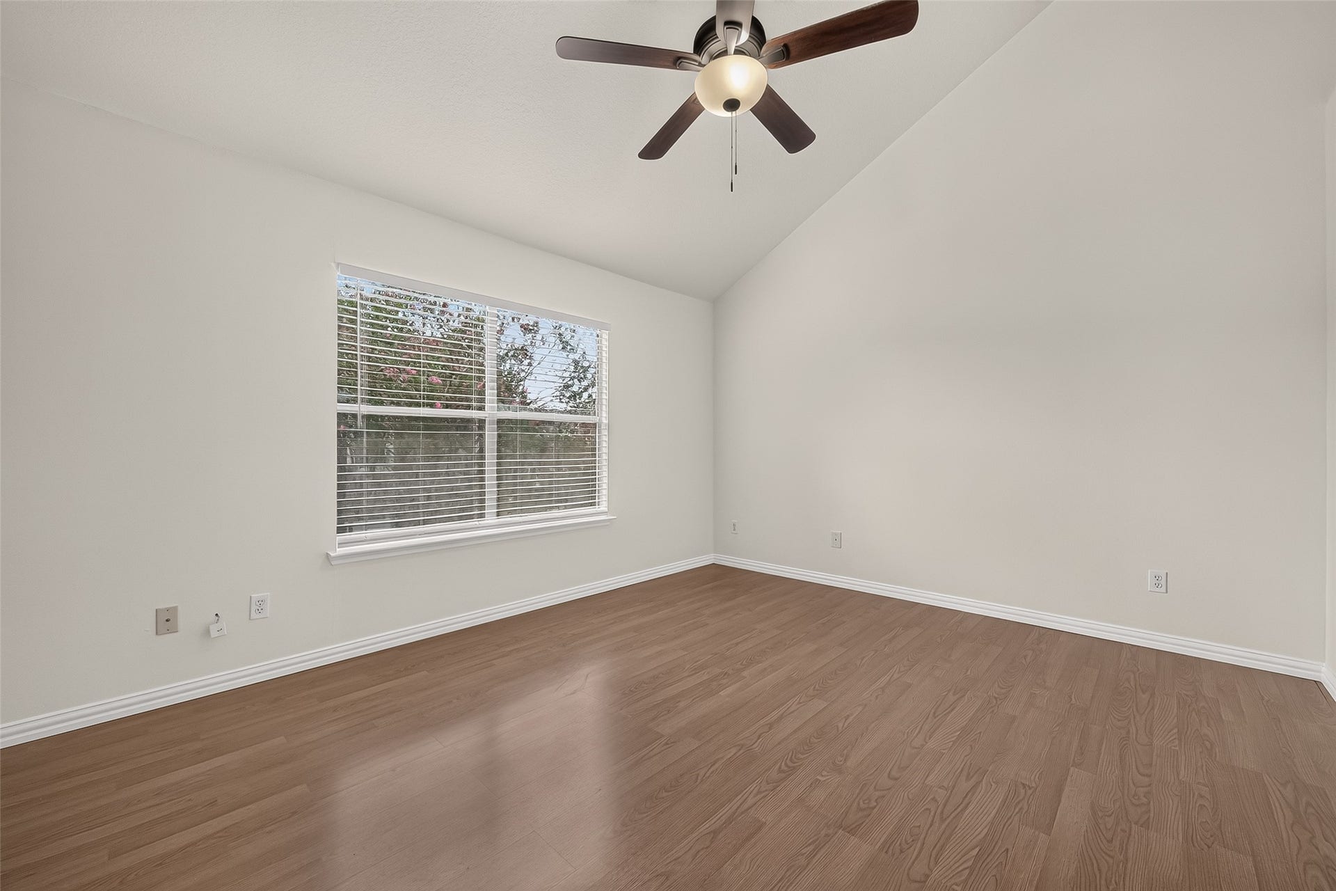2930 Grants Lake Boulevard, #2202, Sugar Land, TX 77479 Comfortable secondary bedroom with vaulted ceiling, ceiling fan, wood-look flooring, large window, and plenty of natural light.
