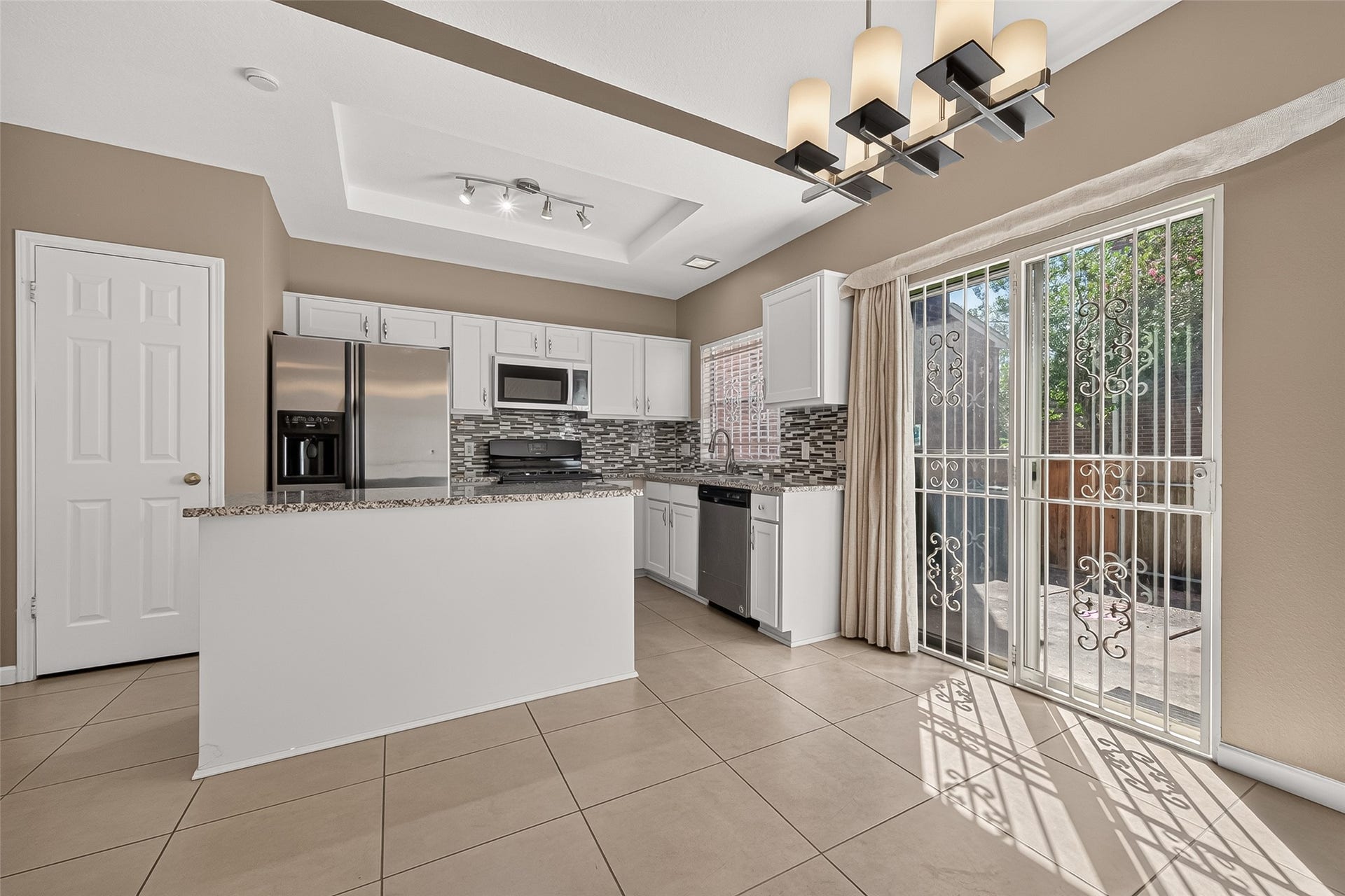 2930 Grants Lake Boulevard, #2202, Sugar Land, TX 77479 Bright, open dining and kitchen area featuring tile flooring, contemporary lighting, granite countertops, stainless-steel appliances, and direct access to the private patio.
