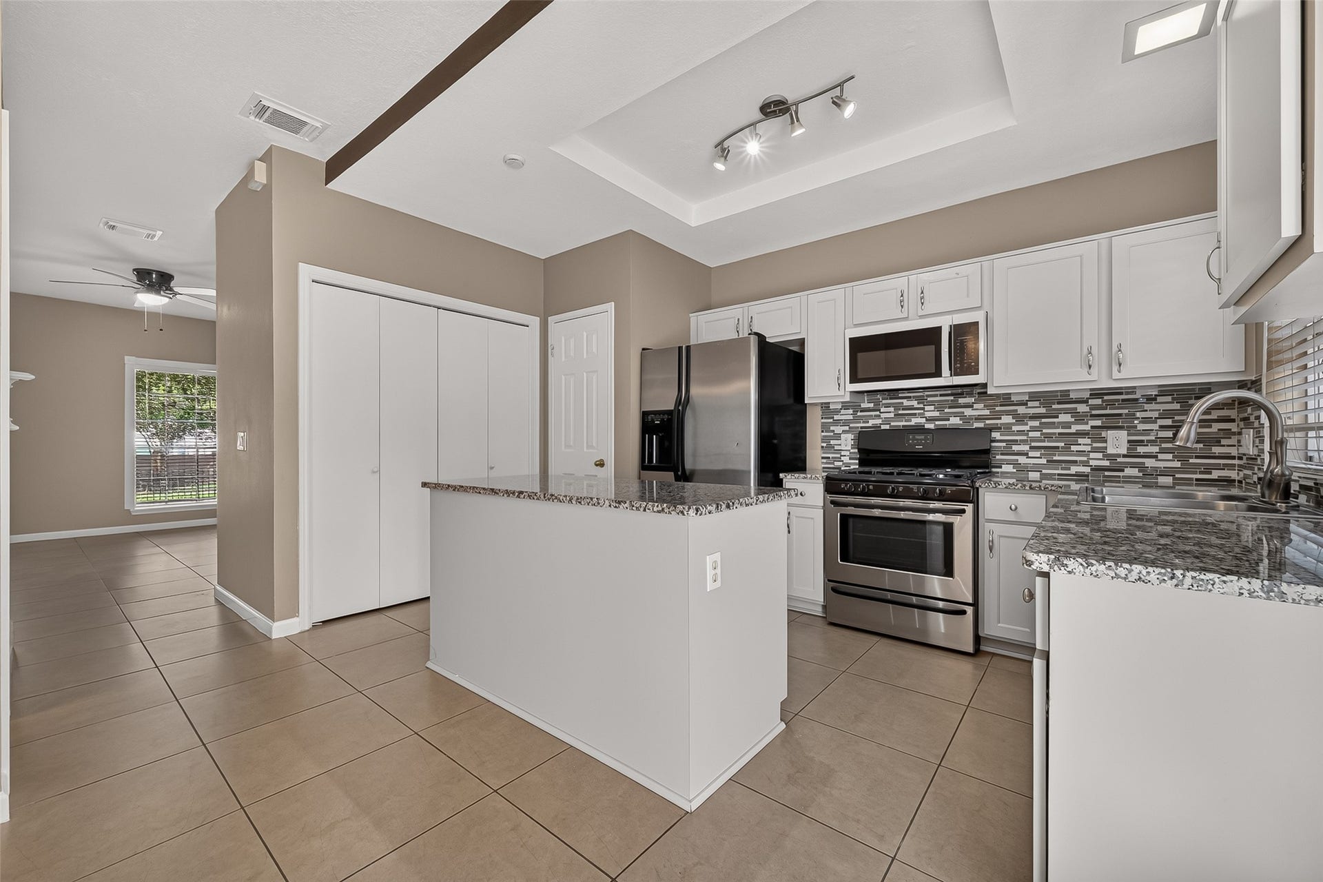 2930 Grants Lake Boulevard, #2202, Sugar Land, TX 77479 Updated kitchen featuring granite countertops, white cabinetry, stainless-steel appliances, decorative tile backsplash, and generous counter space.
