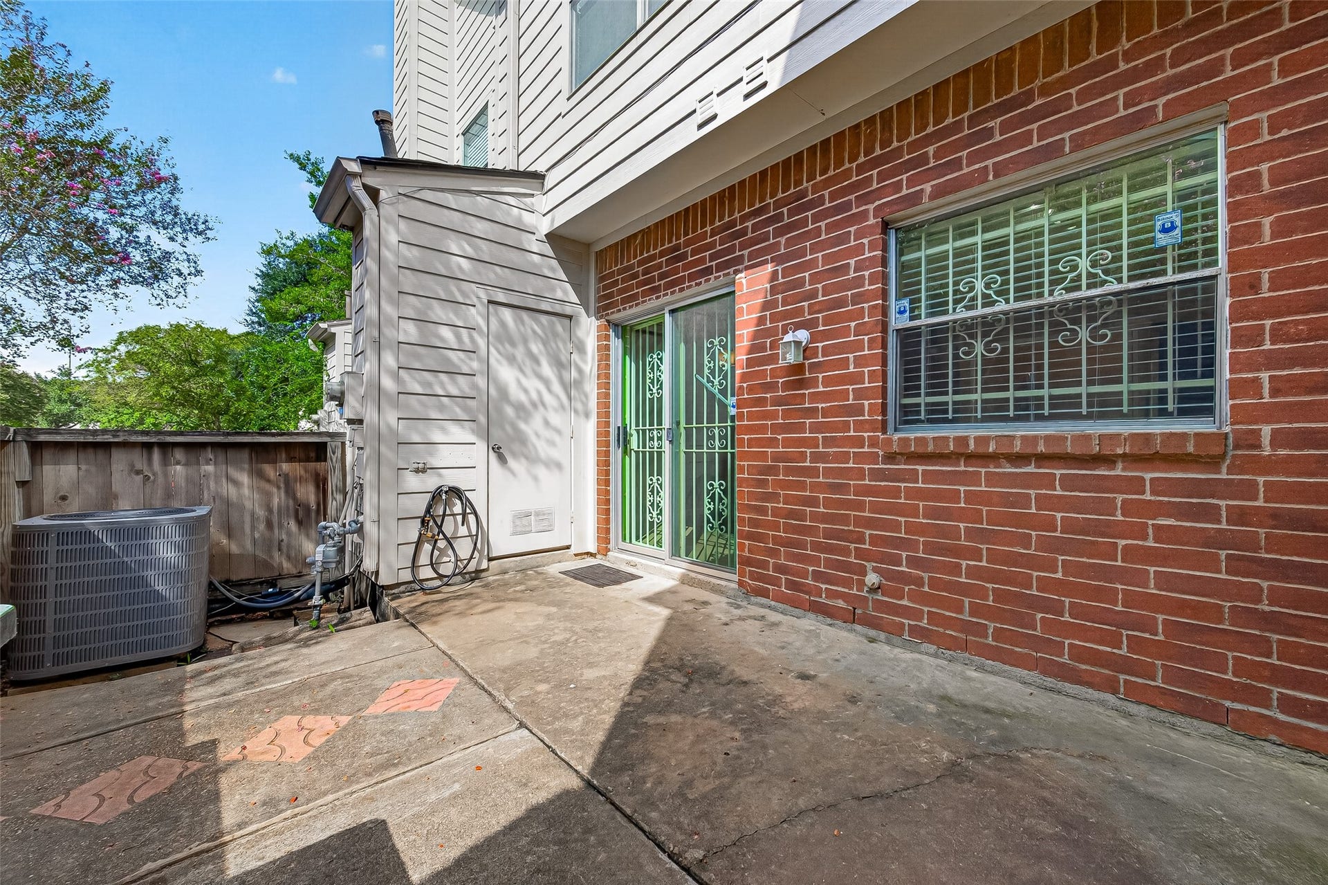 2930 Grants Lake Boulevard, #2202, Sugar Land, TX 77479 Fenced outdoor patio with brick exterior, mature shade trees, and convenient access to the home, offering a private space for relaxing or outdoor seating.