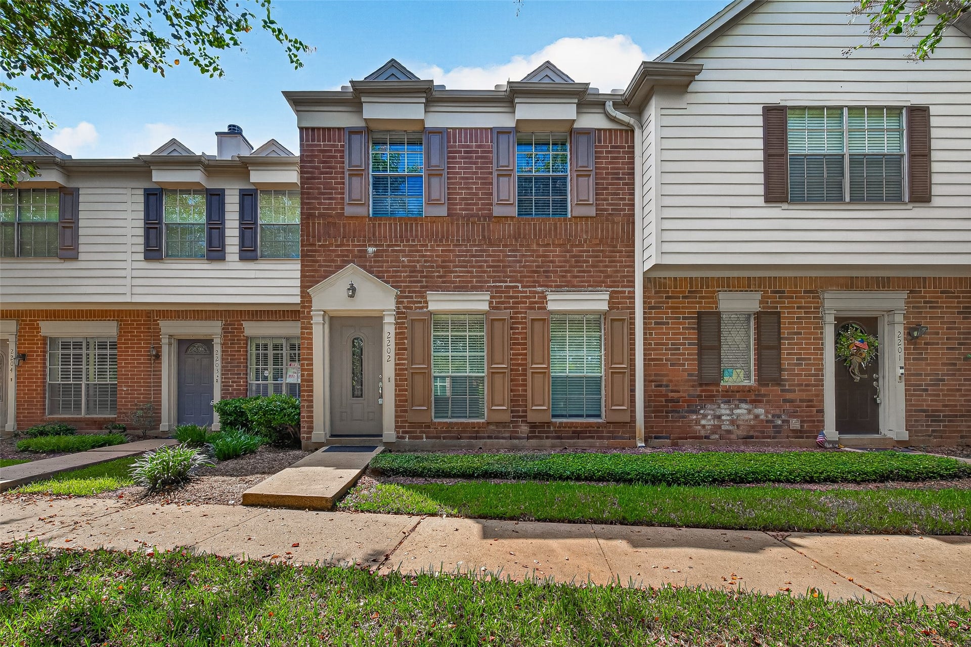 2930 Grants Lake Boulevard, #2202, Sugar Land, TX 77479 Attractive two-story townhouse with classic brick exterior, mature landscaping, and a welcoming front entry.