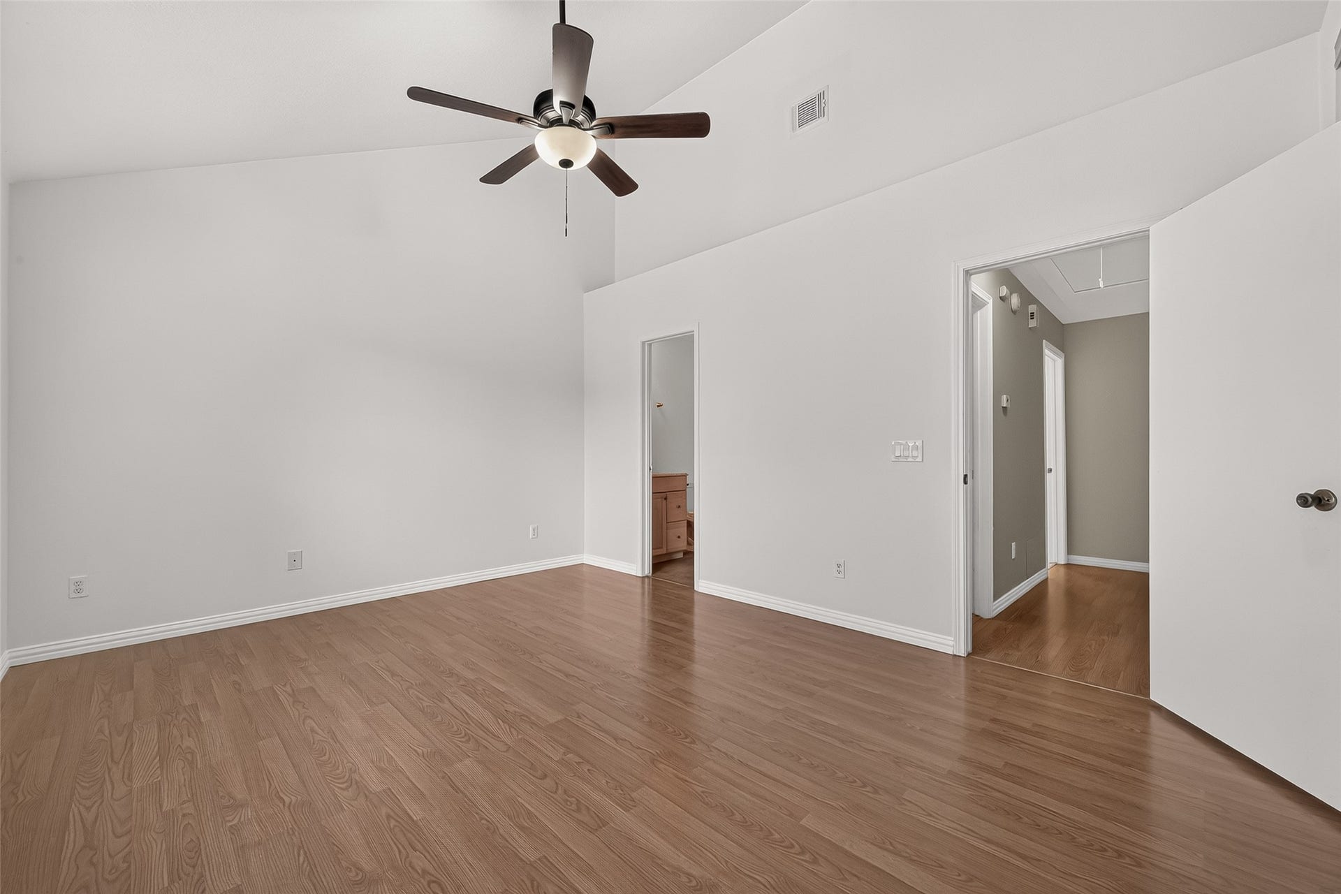 2930 Grants Lake Boulevard, #2202, Sugar Land, TX 77479 Generously sized primary suite with vaulted ceiling, ceiling fan, wood-look flooring, neutral finishes, and convenient access to the en-suite bath.