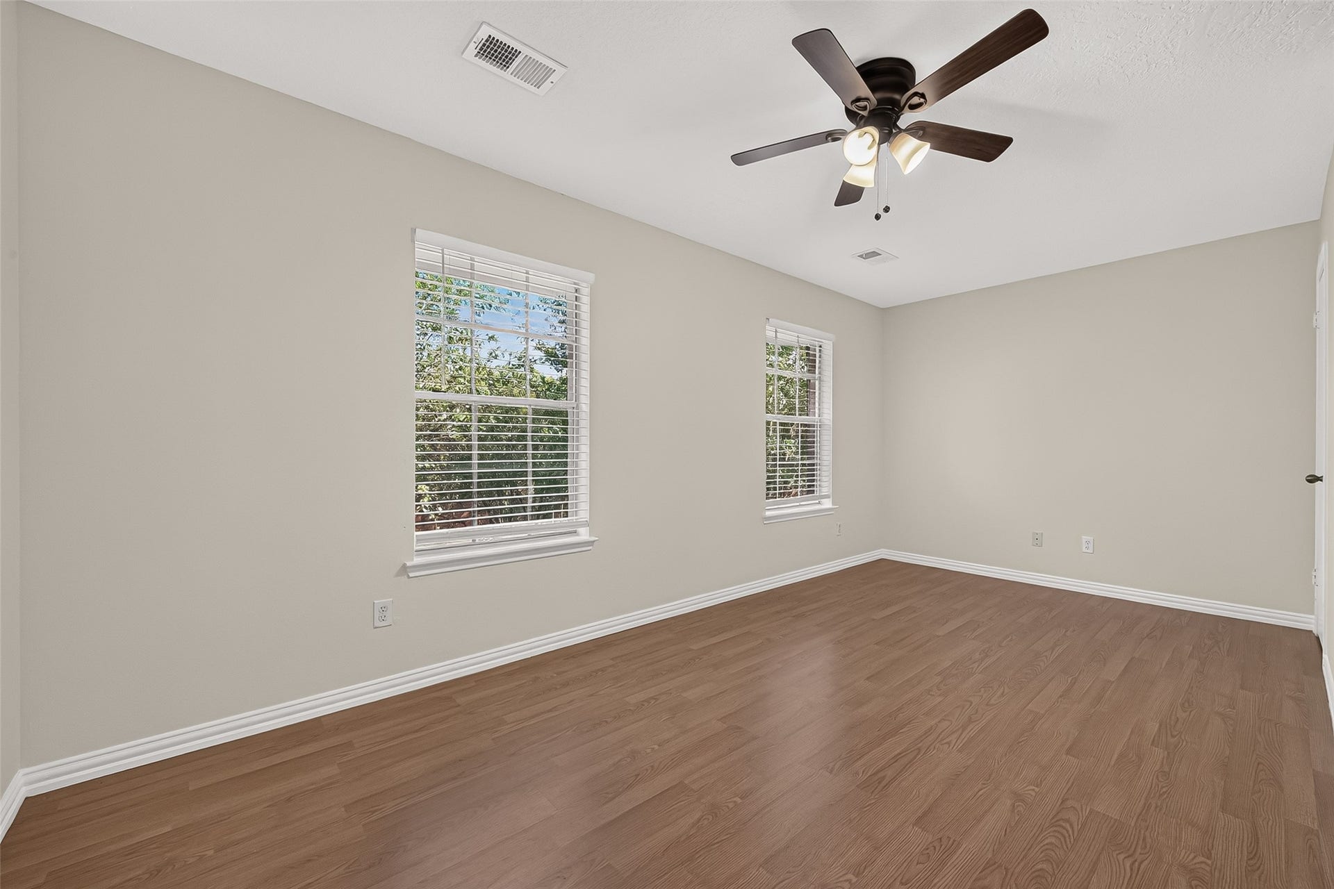 2930 Grants Lake Boulevard, #2202, Sugar Land, TX 77479 Bright and generously sized secondary bedroom featuring wood-look flooring, ceiling fan, neutral finishes, and multiple windows providing abundant natural light.