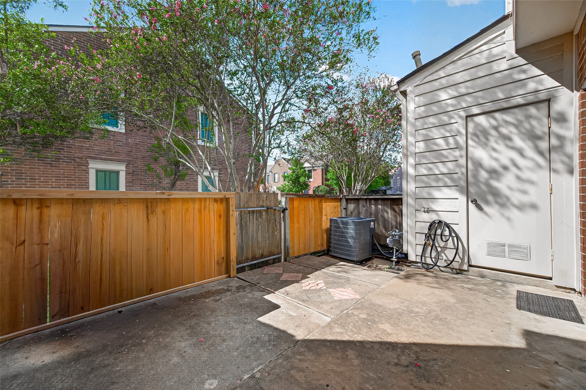 2930 Grants Lake Boulevard, #2202, Sugar Land, TX 77479 Fenced private patio with mature trees nearby, outdoor utility area, and convenient exterior storage access.