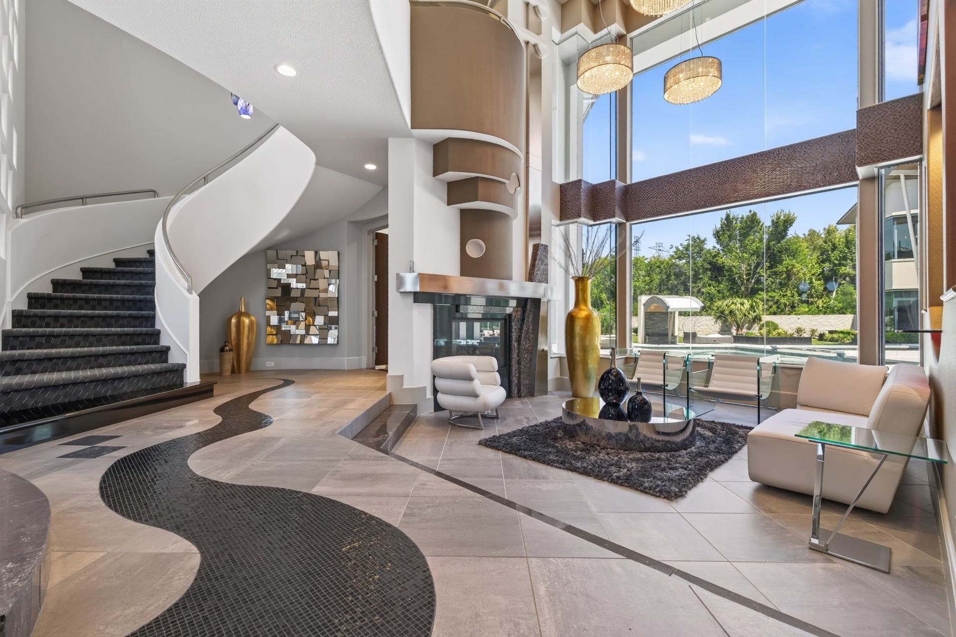 Dramatic main living area with soaring ceilings, architectural staircase and walls of glass overlooking the grounds.