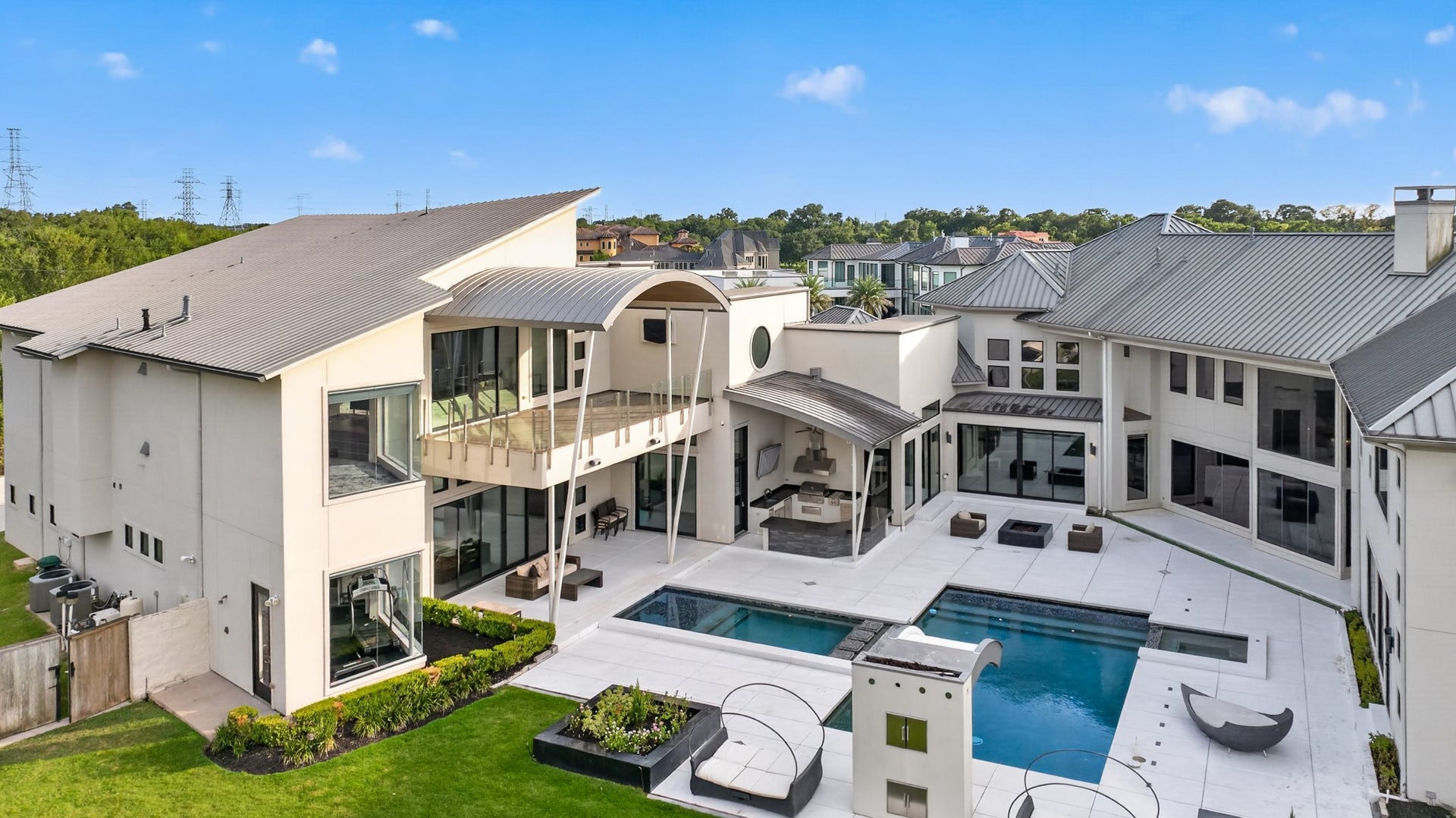 Elevated rear view showcases the homes impressive scale, pool and multiple outdoor living areas.