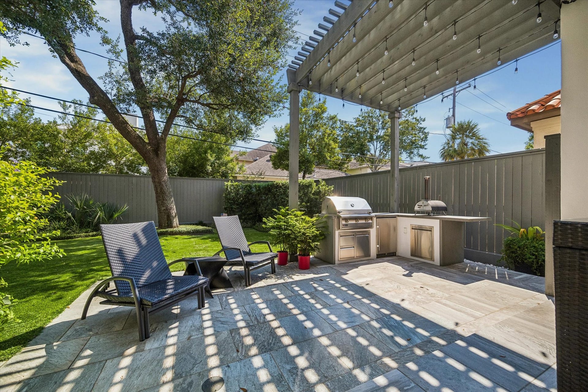 Another view of the outdoor kitchen featuring a 36" 3-burner propane grill, refrigerator, and pizza oven.